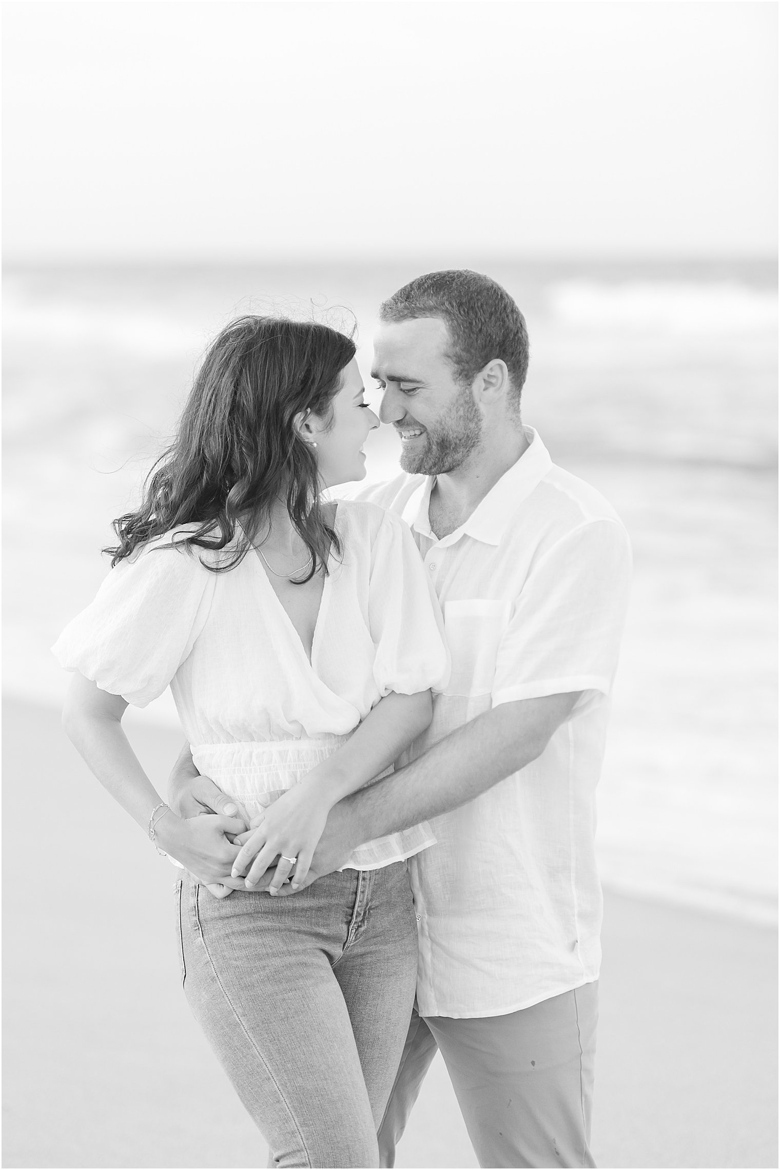 bride and groom hug on beach during engagement photos