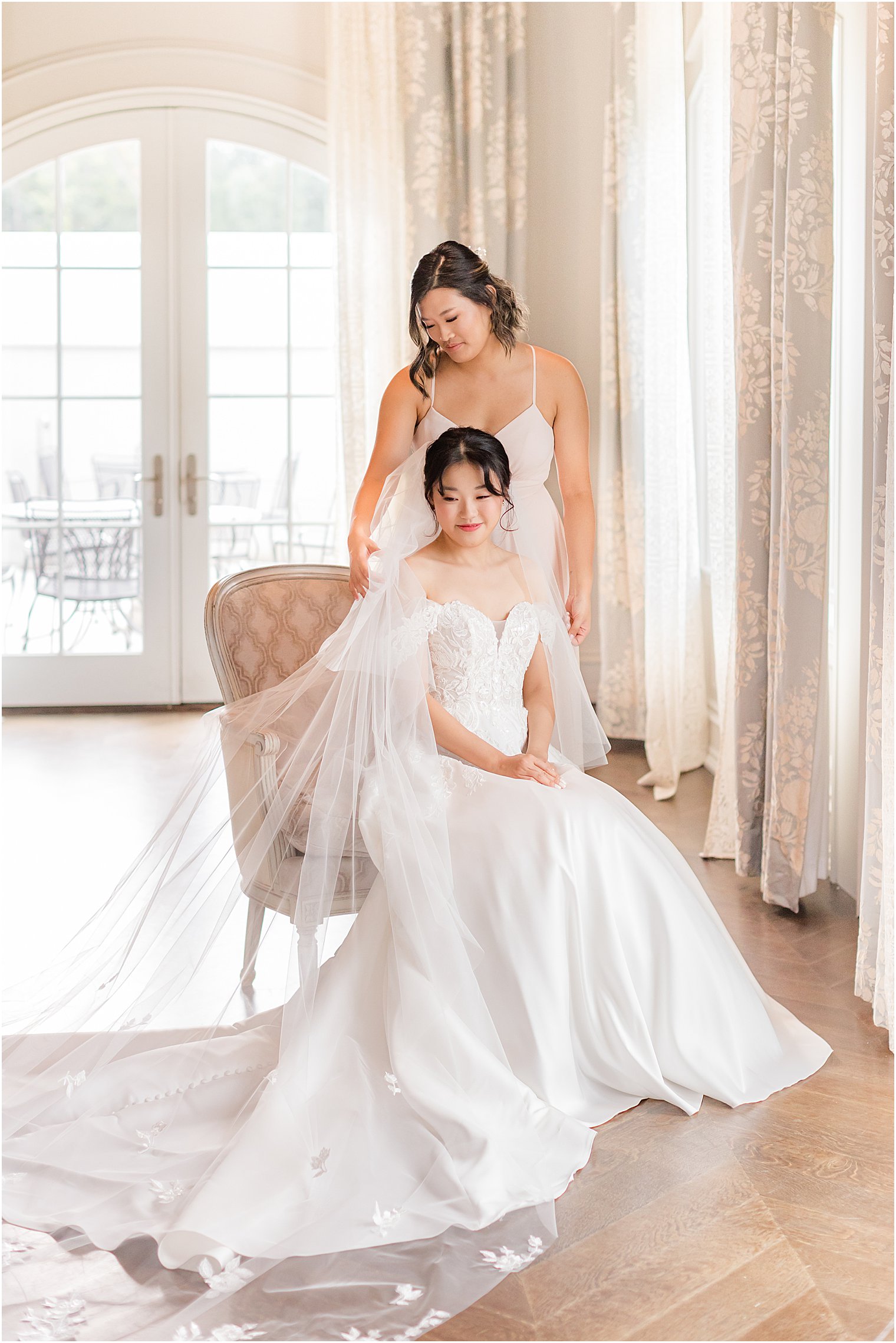 bridesmaid helps adjust veil for bride in suite at Park Chateau Estate 