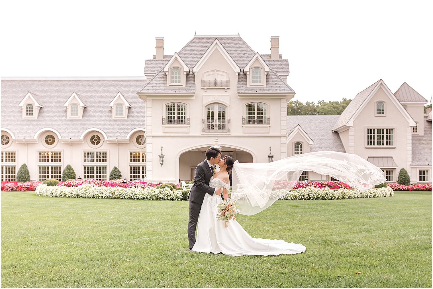 bride and groom kiss with bride's veil floating outside Park Chateau Estate