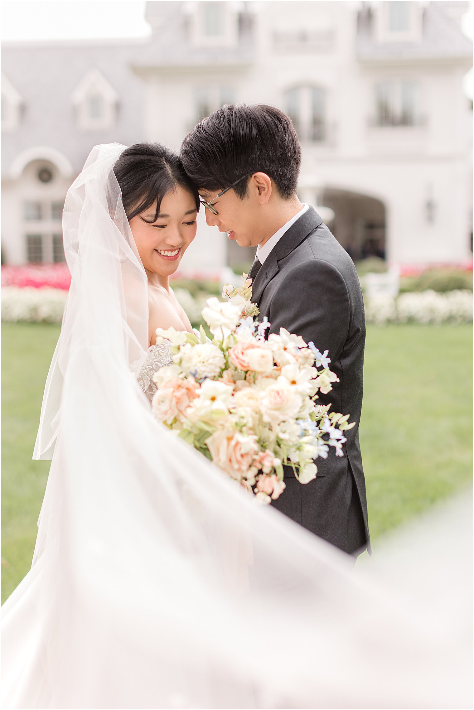 bride and groom laugh with bride's veil outside Park Chateau Estate