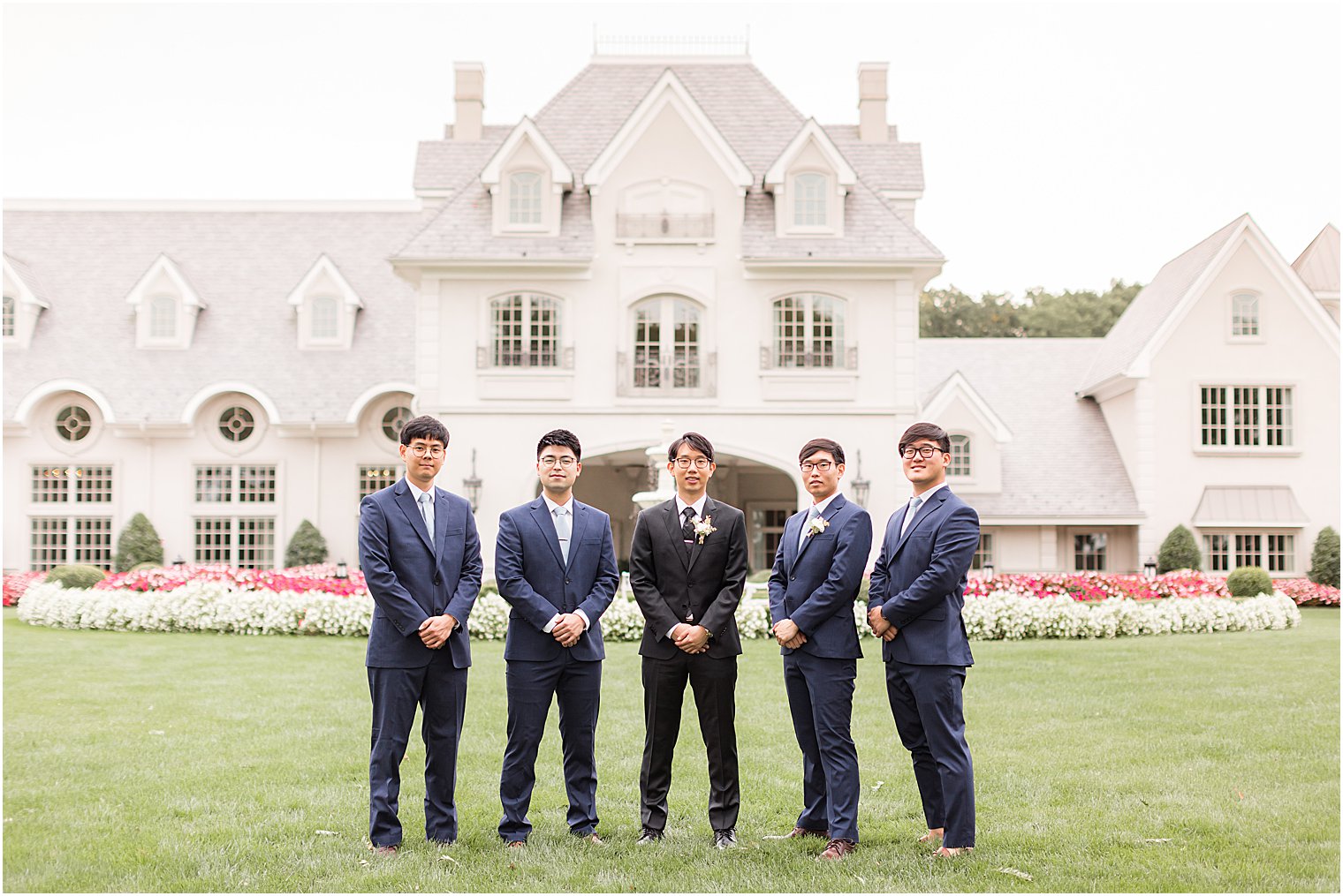 groom and groomsmen stand on lawn at Park Chateau Estate