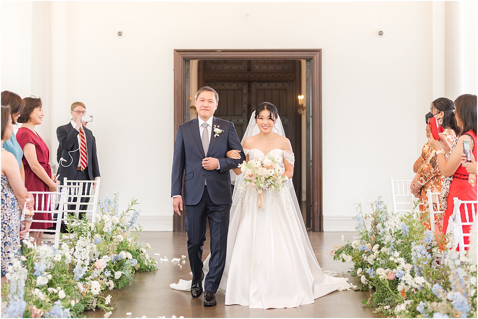 bride enters wedding ceremony in Park Chateau chapel with floral lined aisle