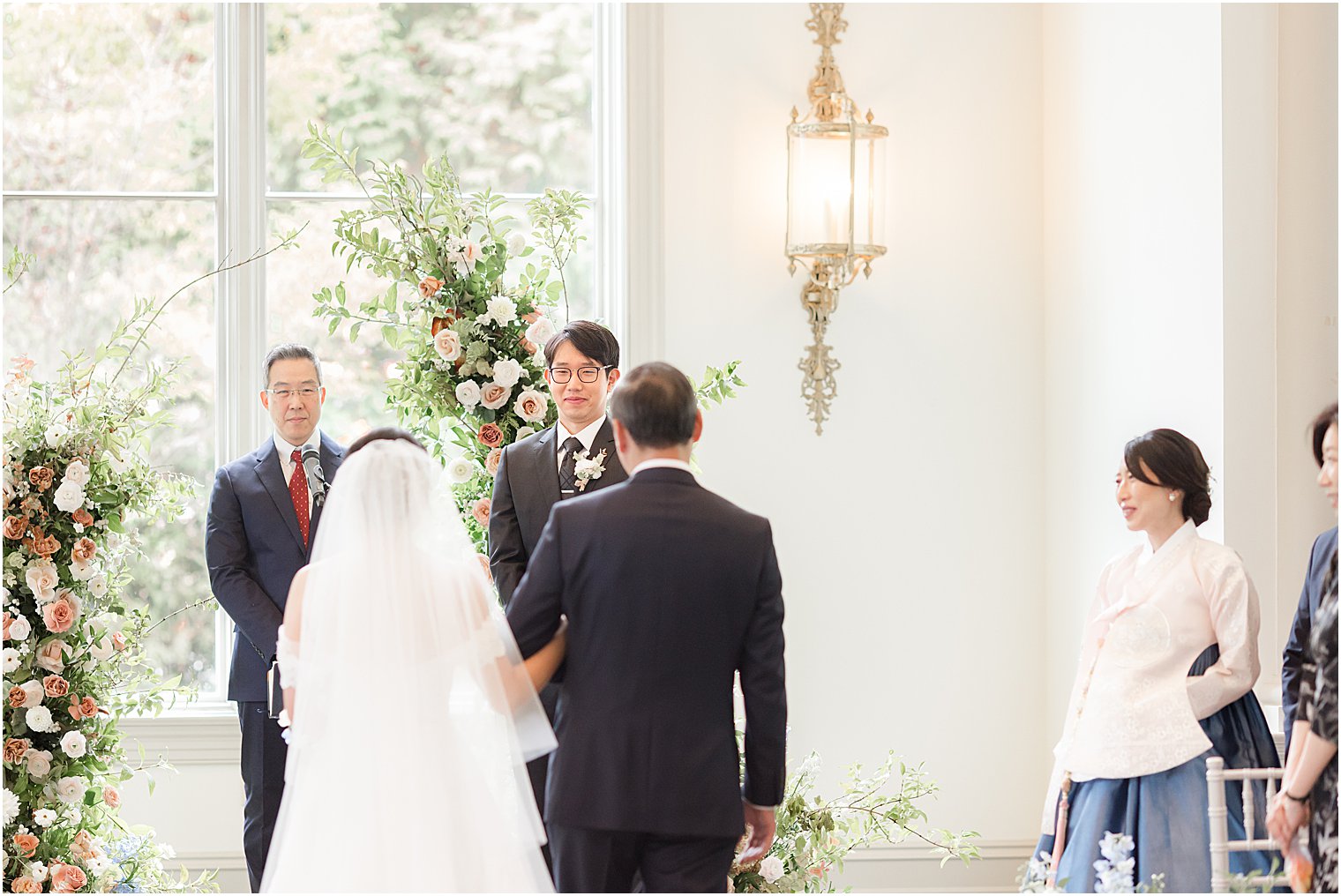 groom smiles at bride during ceremony in Park Chateau chapel