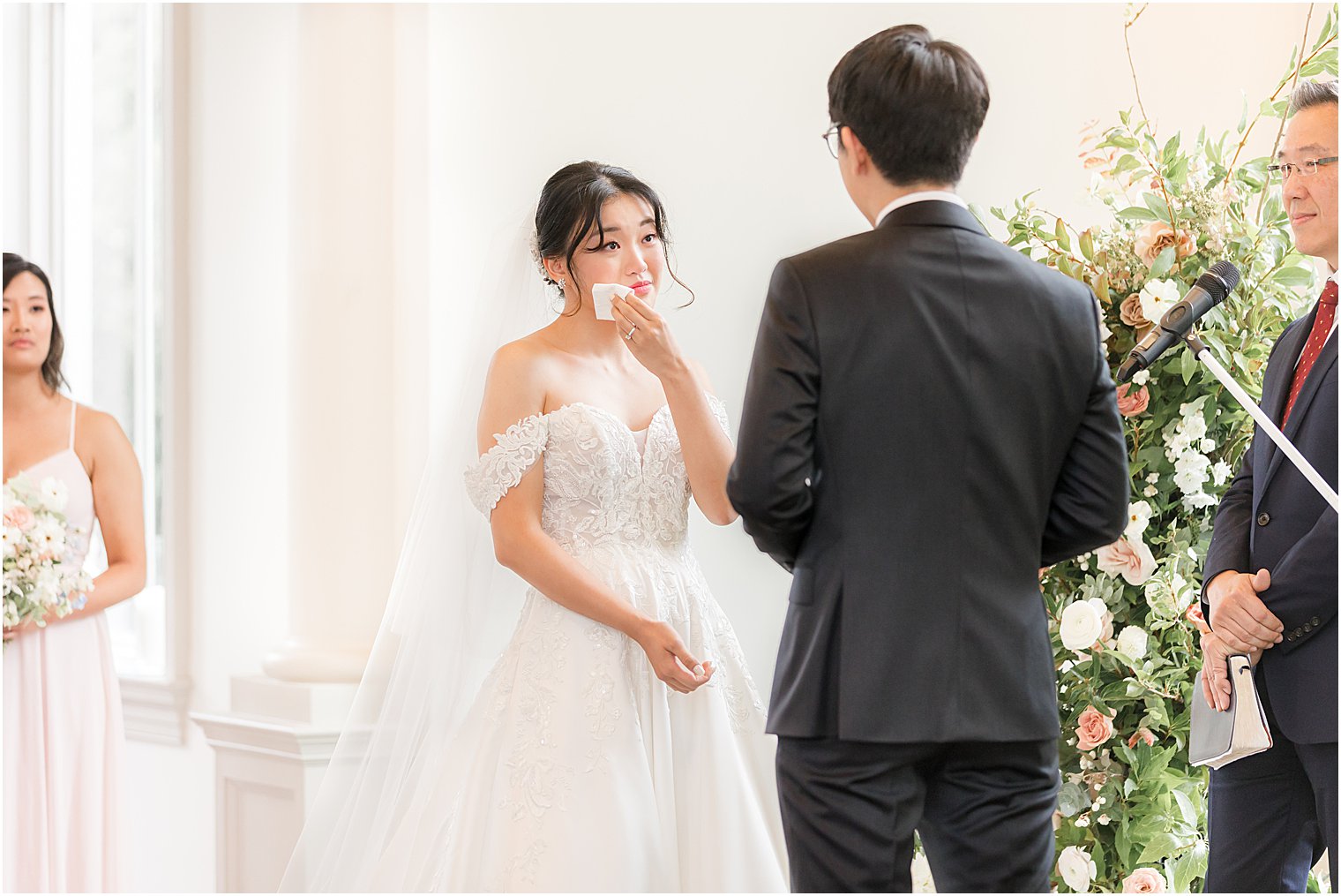 bride wipes away tear during ceremony in Park Chateau chapel