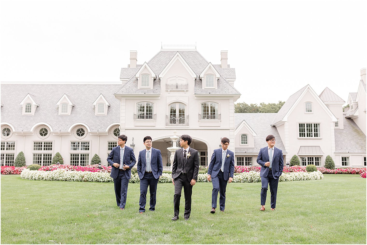 groom and groomsmen walk across lawn at Park Chateau Estate