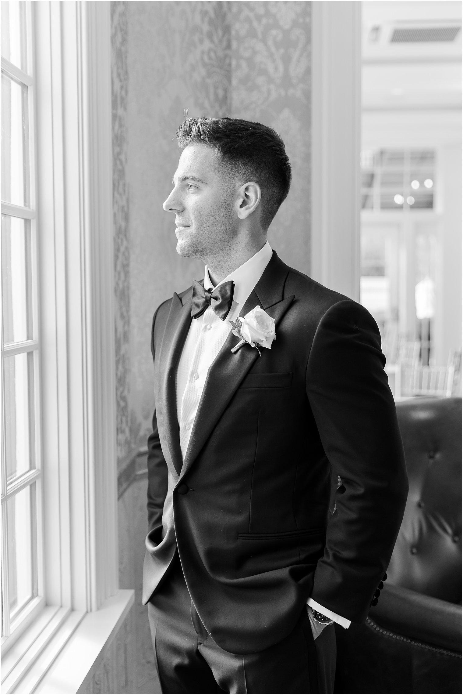 black and white portrait of groom looking out the window at Shadowbrook at Shrewsbury