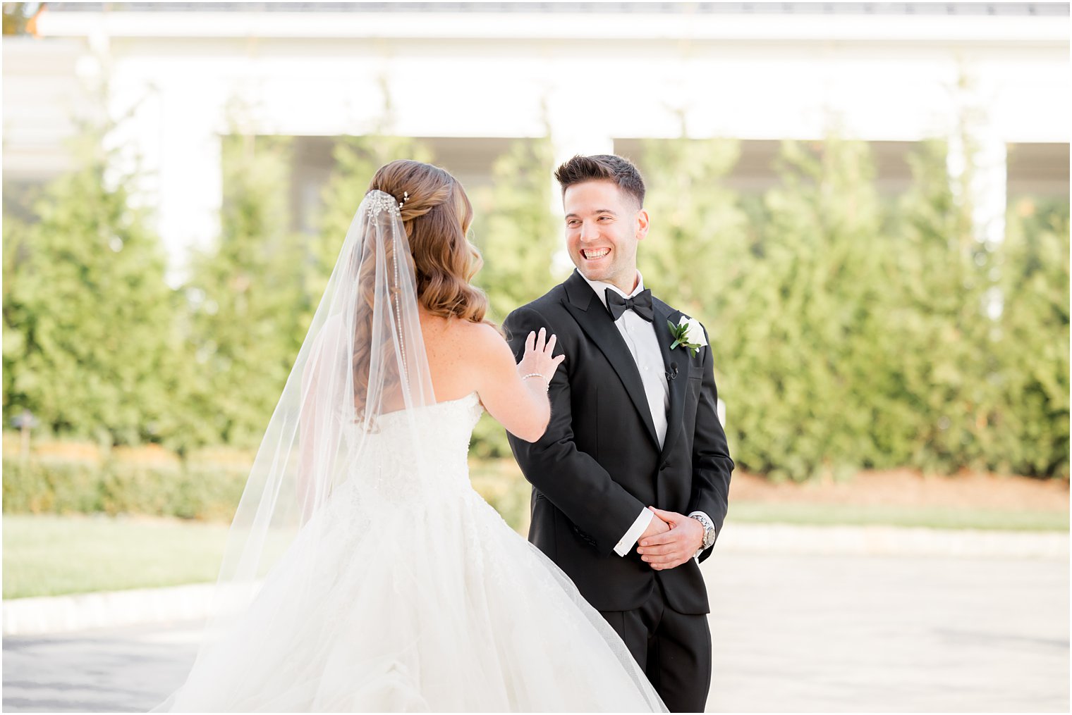 bride reaches for groom's shoulder during first look 