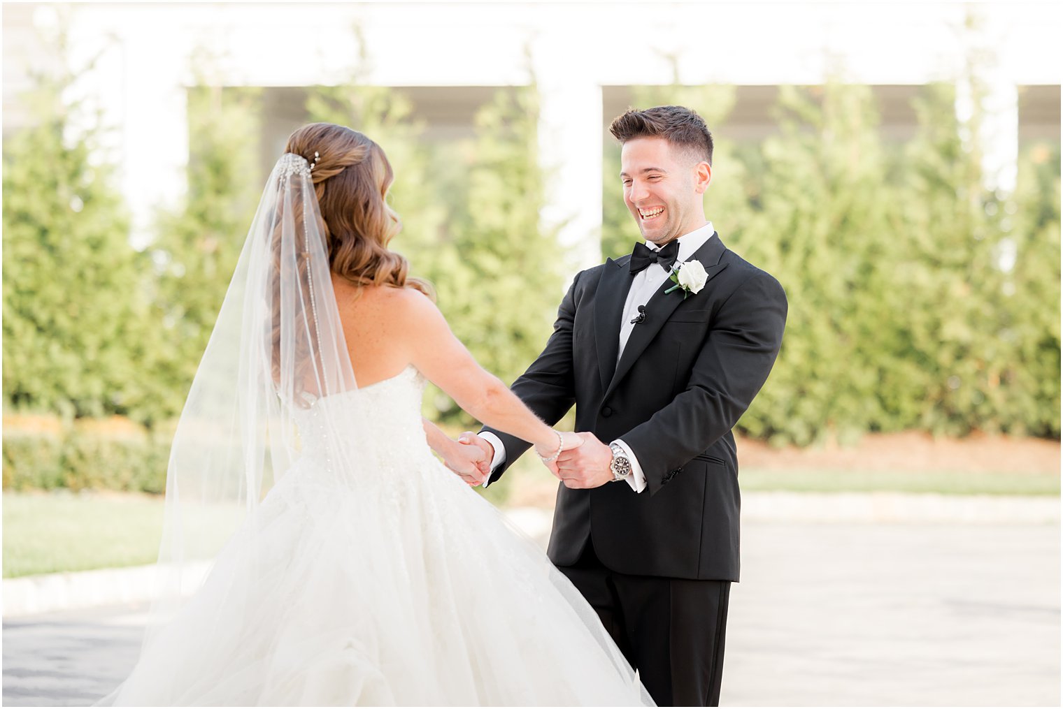 groom holds bride's hands during first look at Shadowbrook at Shrewsbury