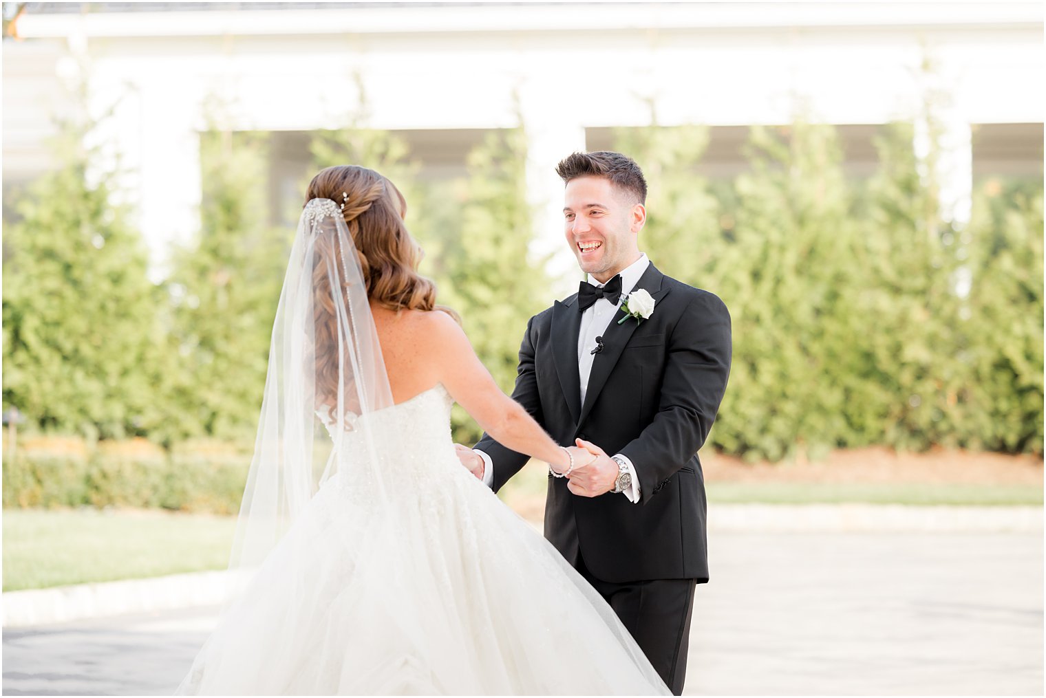 groom smiles at bride holding her hands during first look at Shadowbrook at Shrewsbury