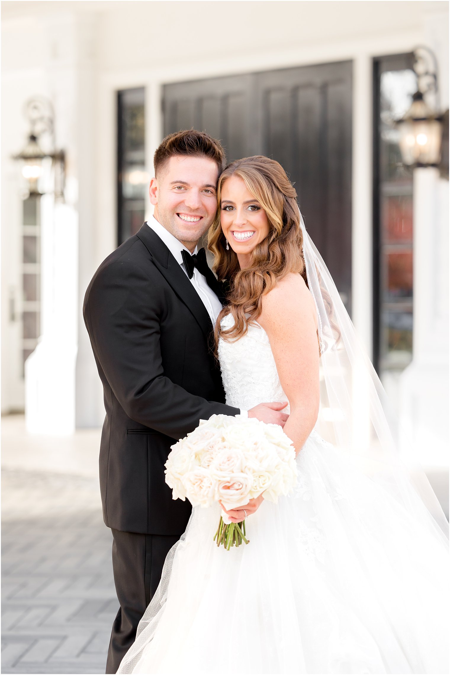 bride and groom lean heads together standing outside Shadowbrook at Shrewsbury