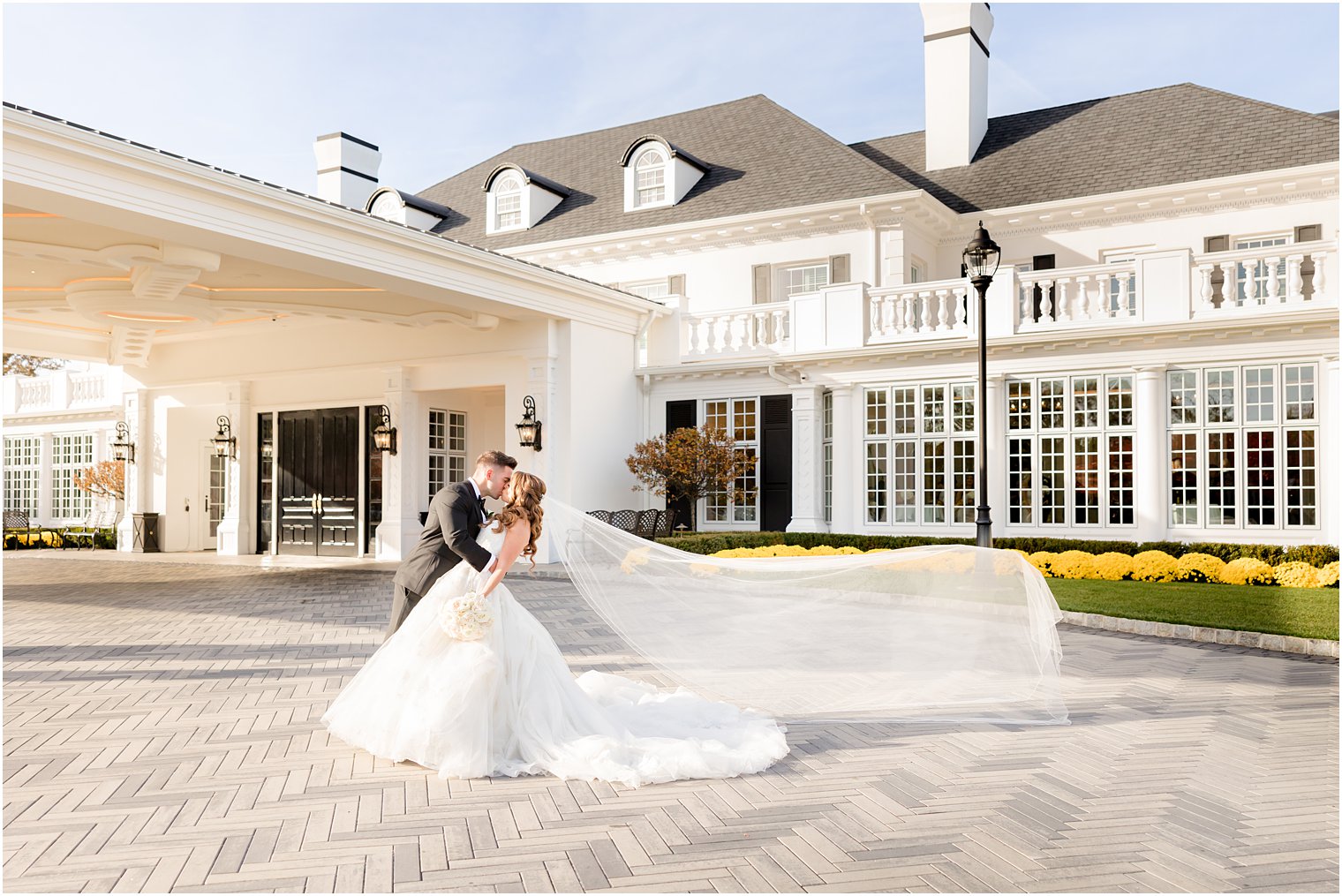 groom kisses bride with veil floating behind them at Shadowbrook at Shrewsbury