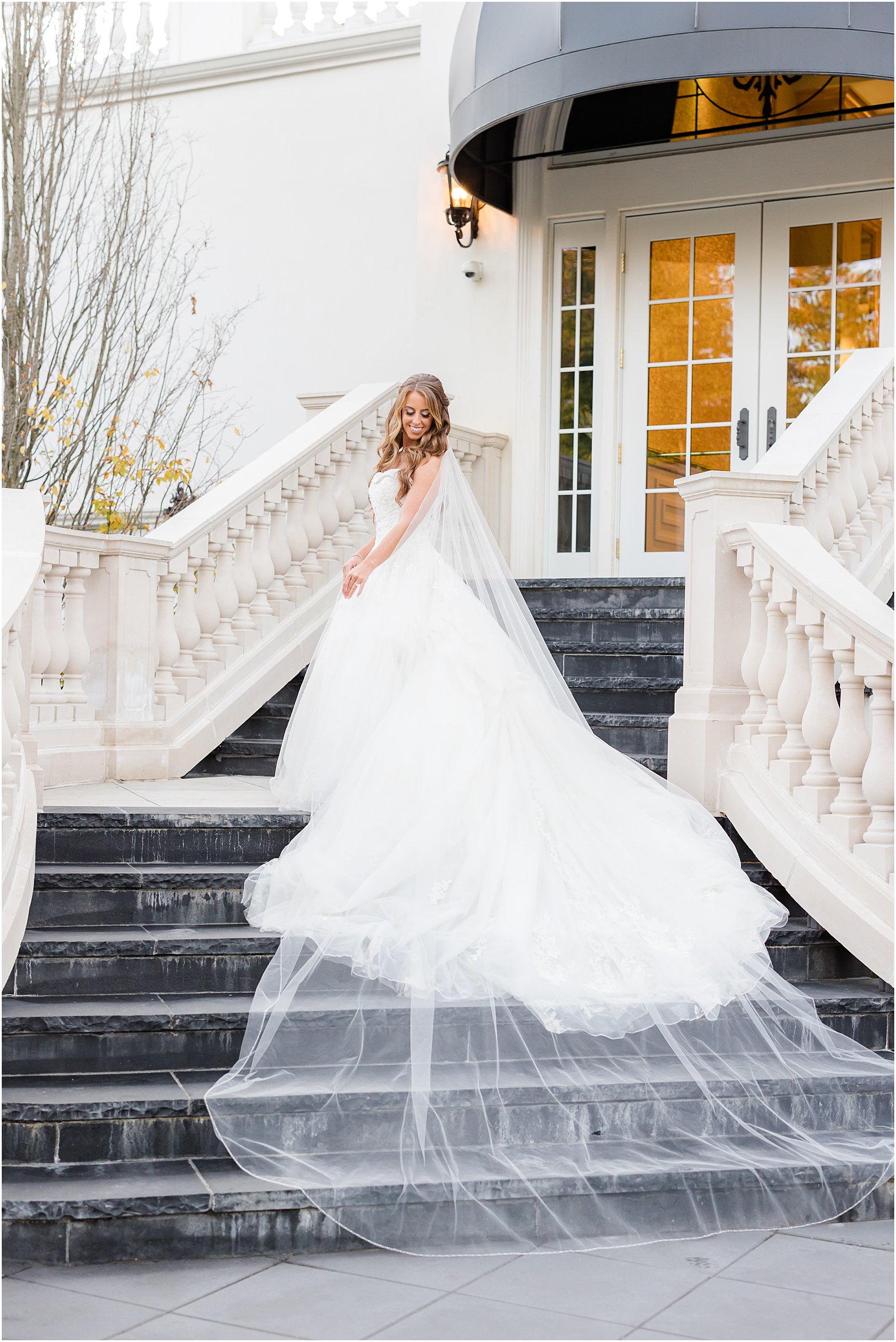 bride stands on staircase at Shadowbrook at Shrewsbury