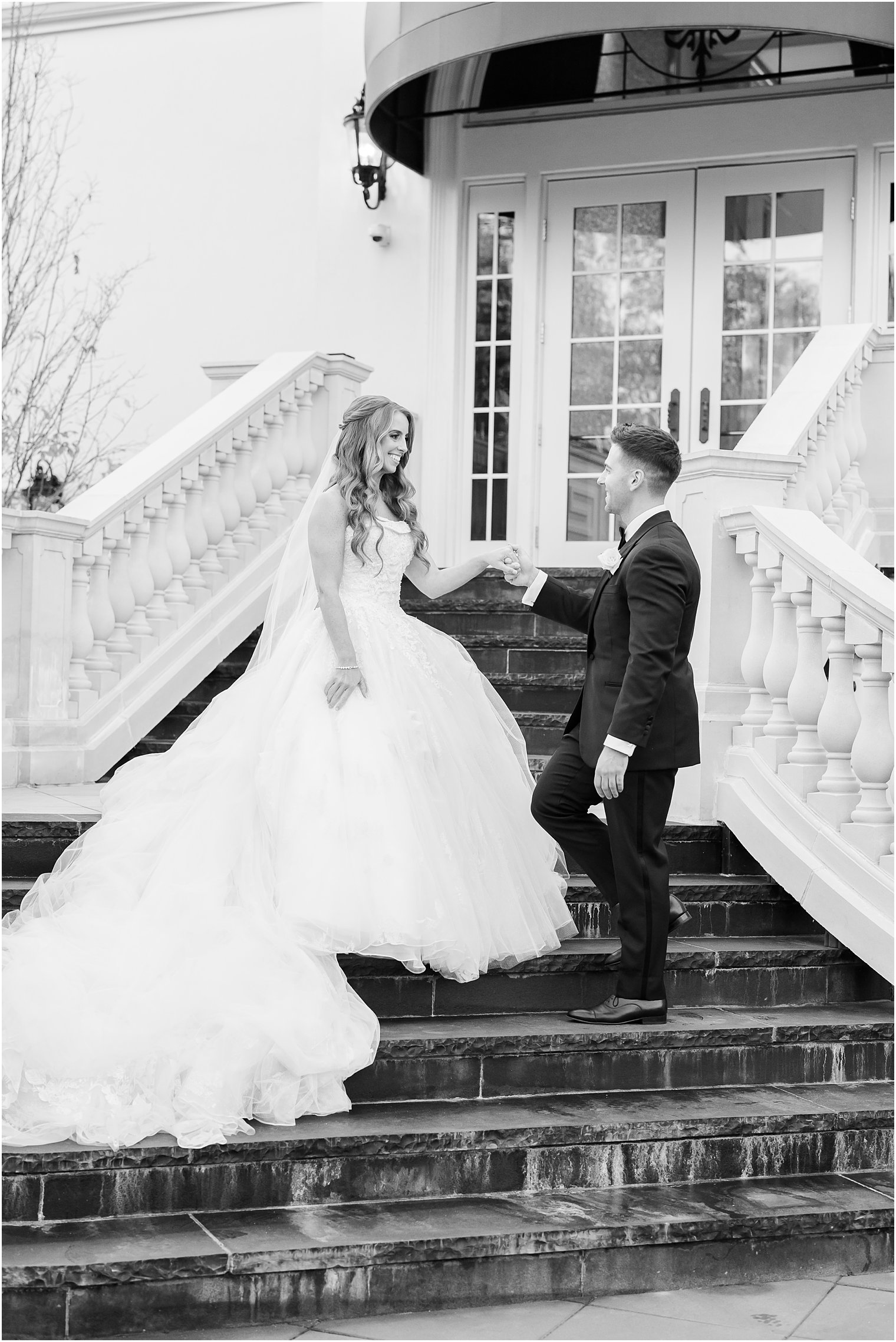 groom leads bride in strapless wedding gown down steps at Shadowbrook at Shrewsbury