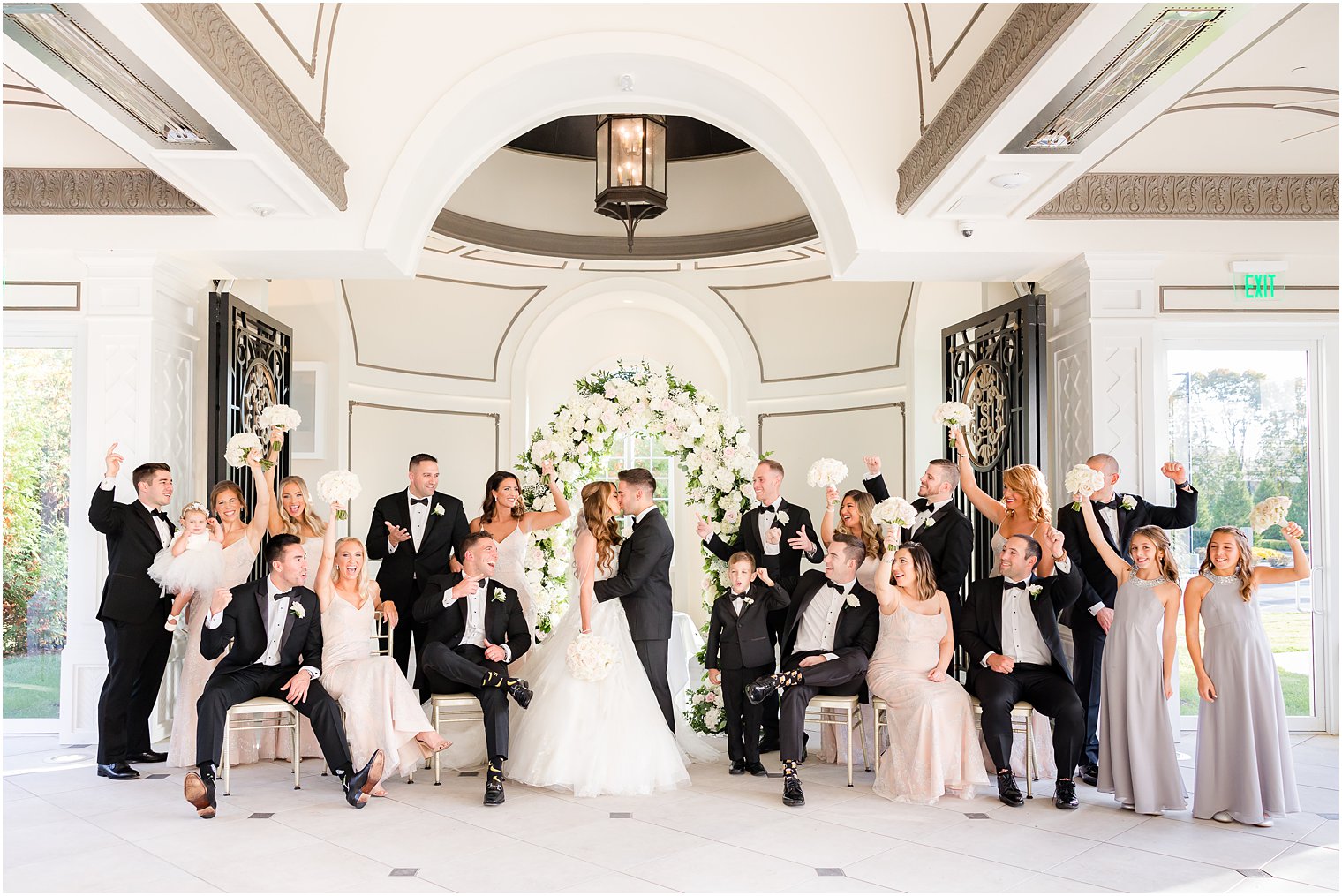 bride and groom kiss in chapel at Shadowbrook at Sherwsbury surrounded by wedding party 