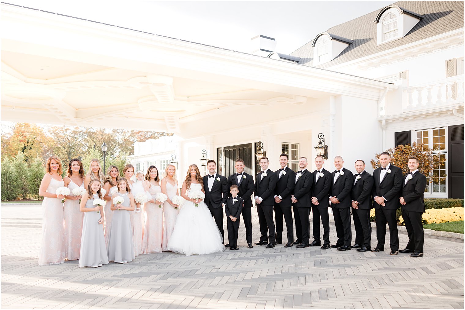 bride and groom stand with wedding party outside Shadowbrook at Sherwsbury