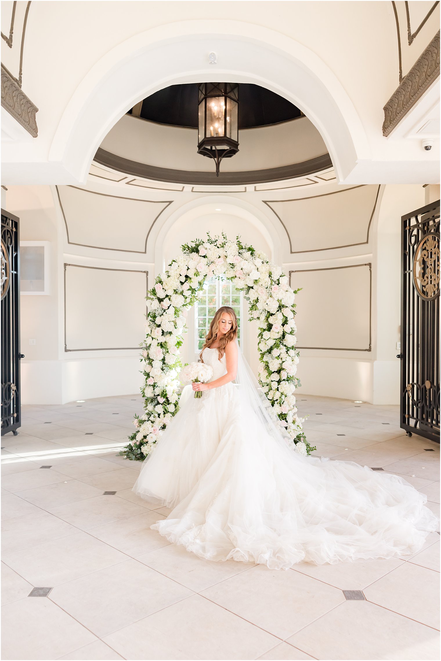 bride stands in chapel by trellis of white roses at Shadowbrook at Sherwsbury