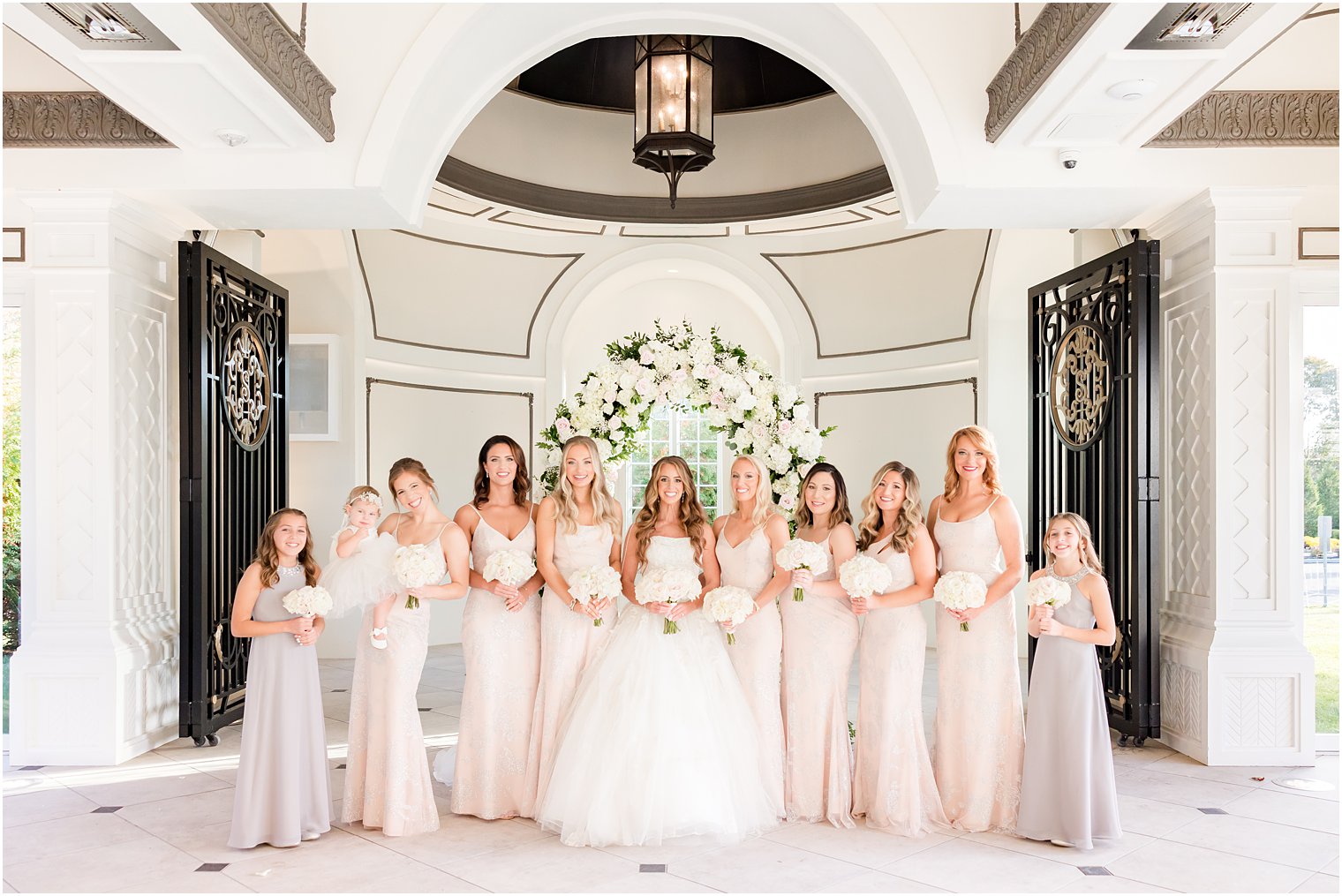 bride stands with bridesmaids in pink and grey in New Jersey 
