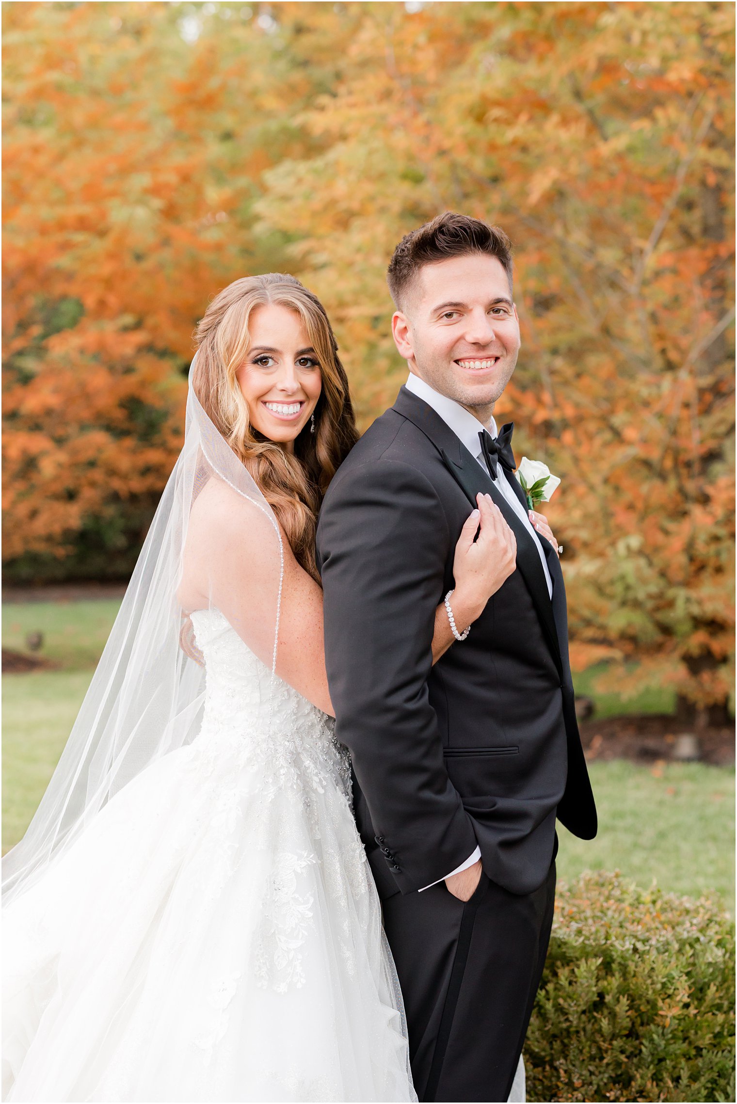 bride hugs groom from behind during fall wedding portraits 