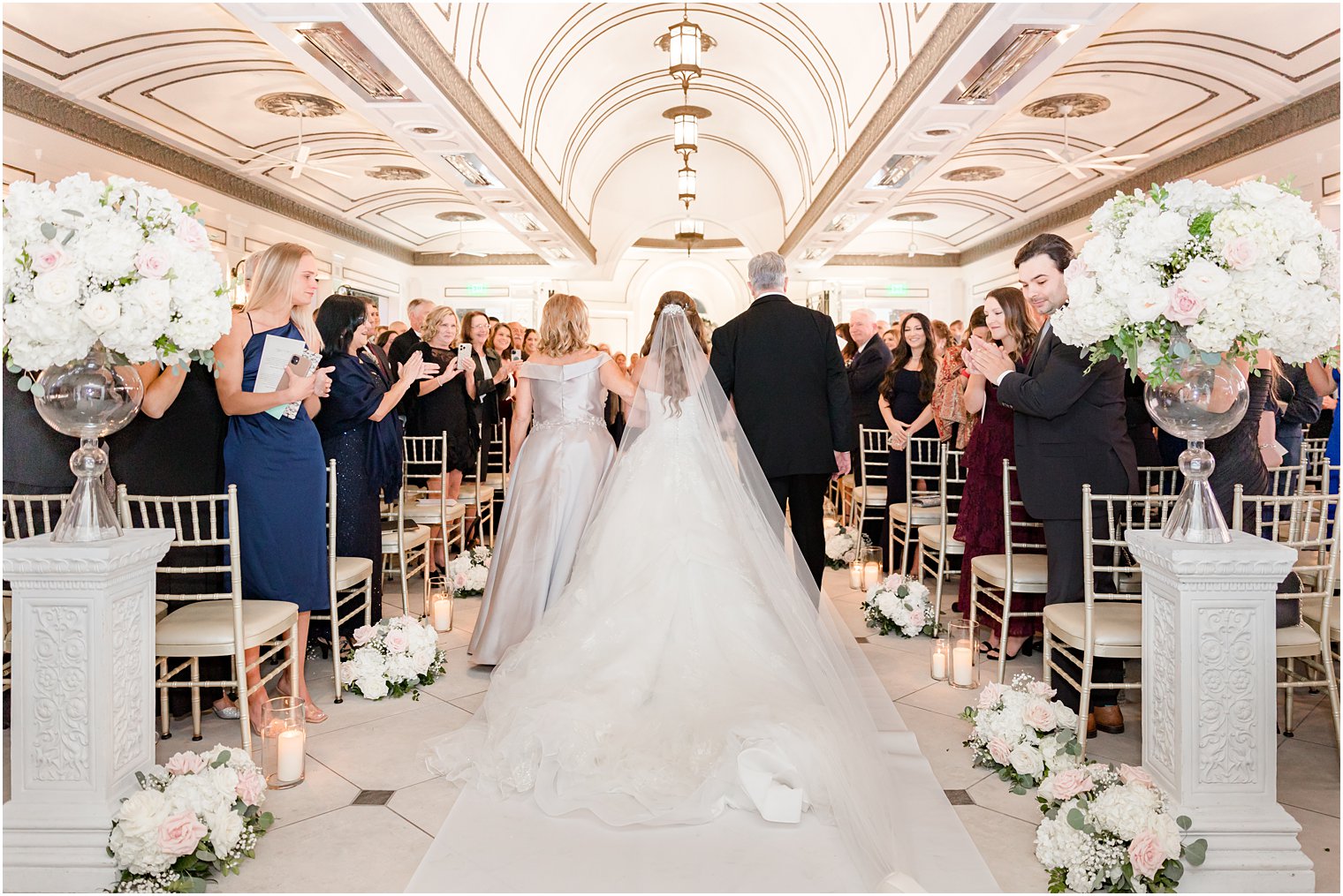 bride walks down aisle with mom and dad during wedding ceremony 