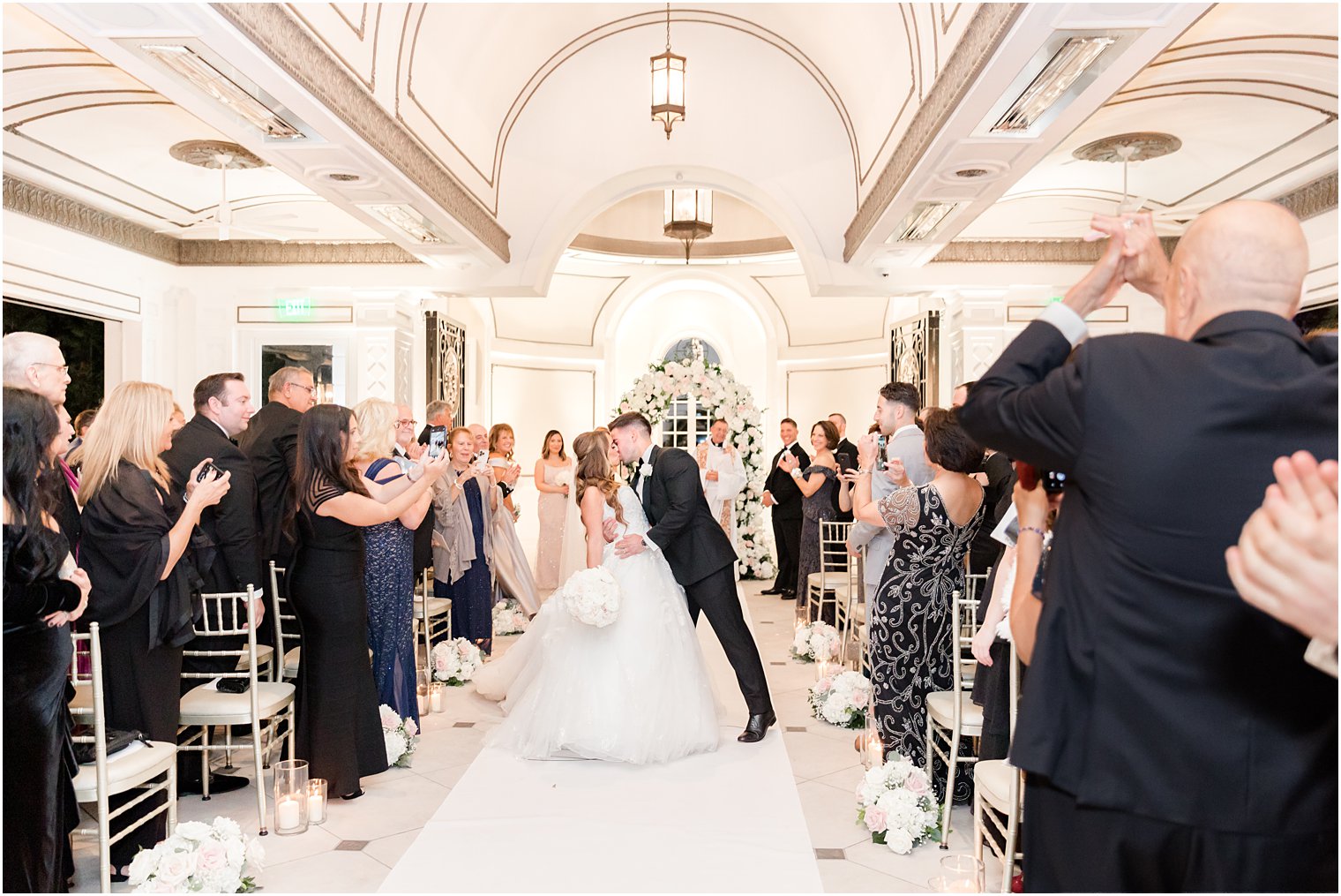 groom dips bride kissing her in aisle of chapel at Shadowbrook at Shrewsbury