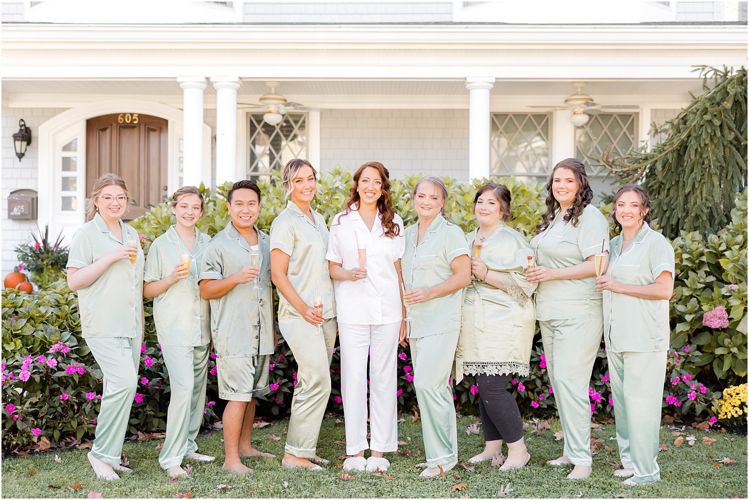 bride poses with bridesmaids in front of New Jersey house 