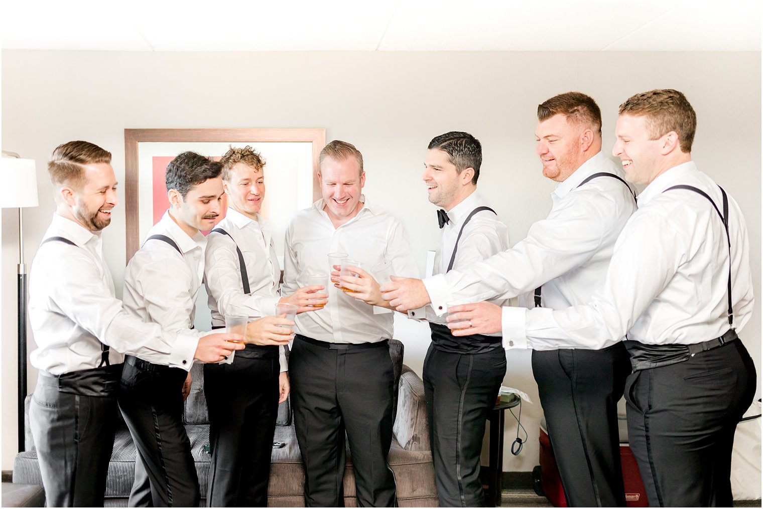 groom and groomsmen toast in black pants and suspenders 