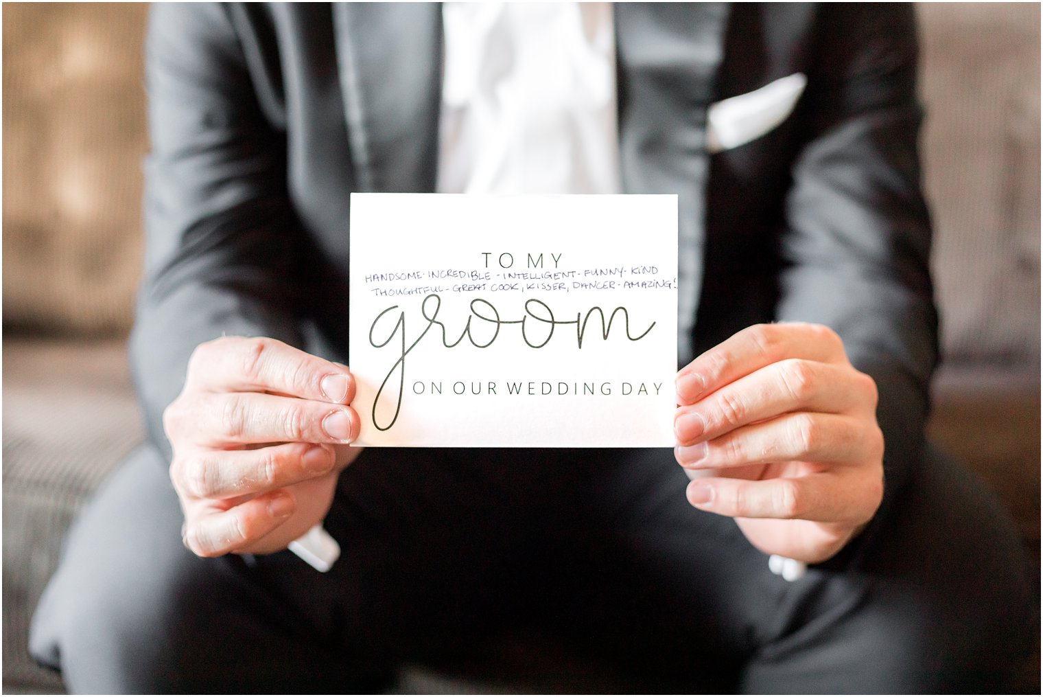 groom holds card on wedding morning from bride 