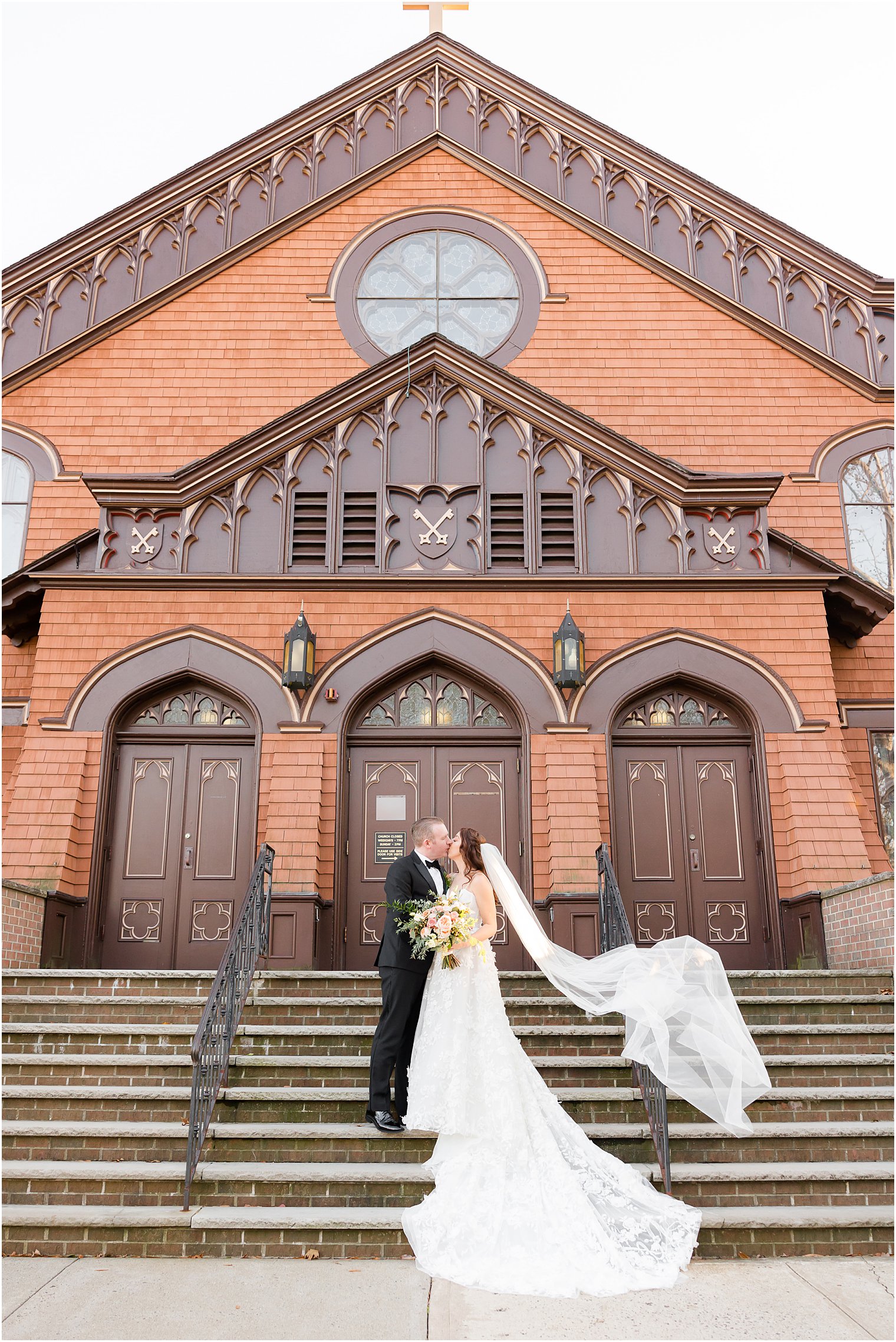 bride and groom kiss on church steps at St. Peter's Church in Point Pleasant