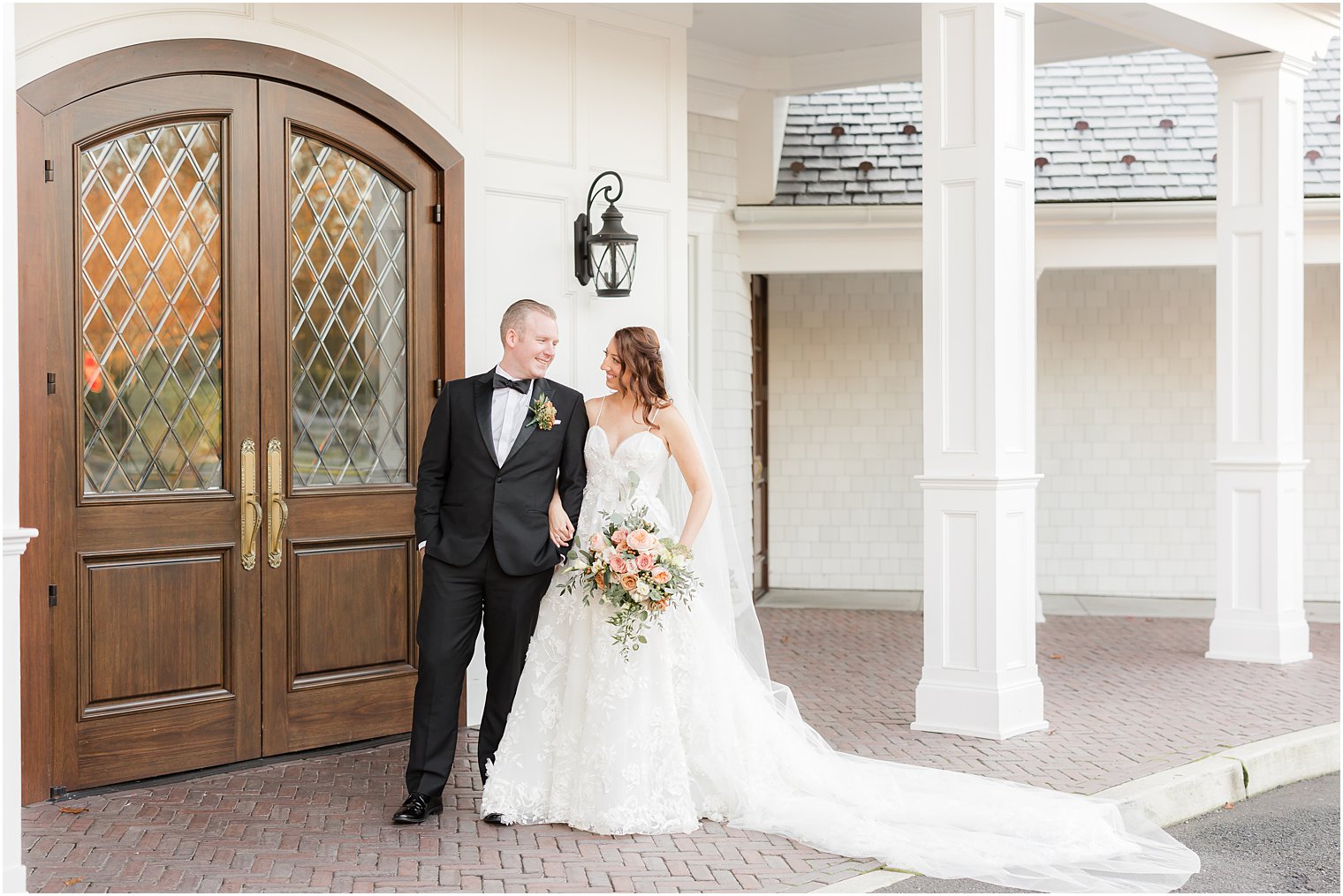 bride and groom smile together walking along front of The Mill Lakeside Manor