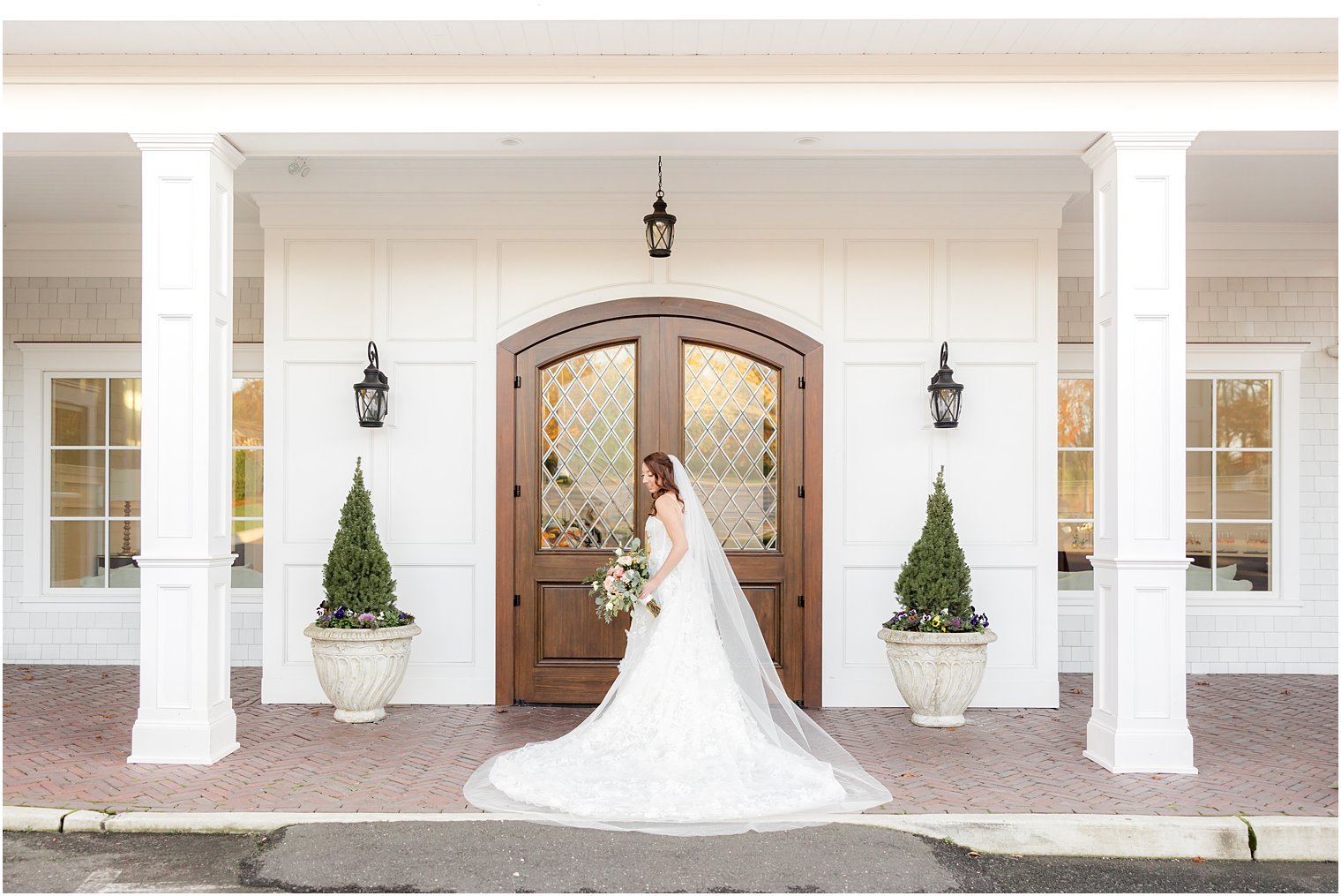 bride stands by wooden doors of The Mill Lakeside Manor with wedding dress around her 