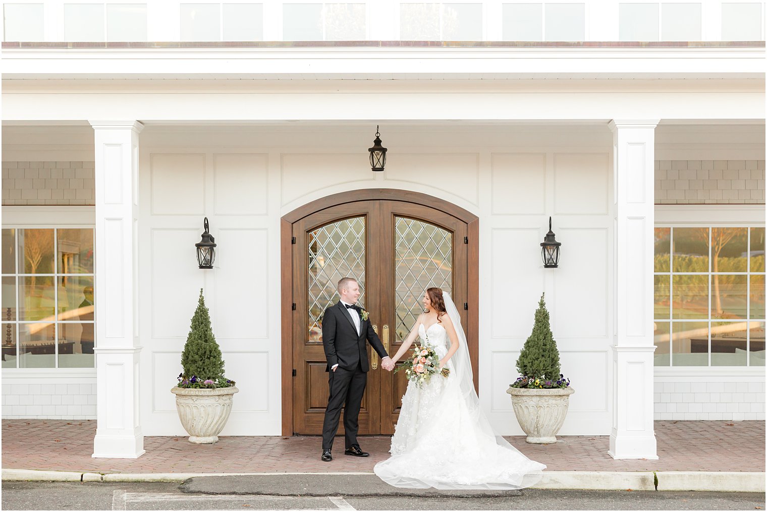 bride and groom hold hands by wooden door at The Mill Lakeside Manor