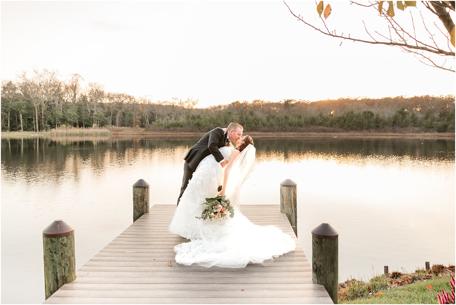 groom kisses bride on dock dipping her at The Mill Lakeside Manor