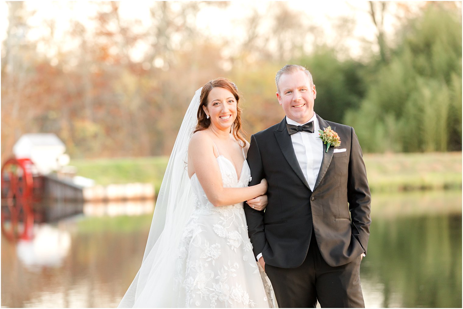 bride holds groom's arm standing on dock at The Mill Lakeside Manor