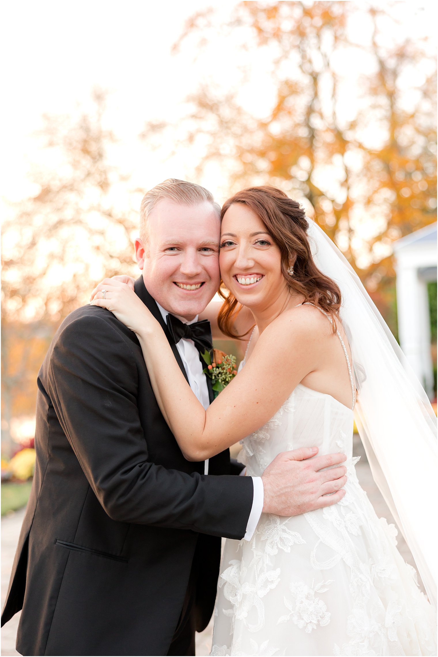 bride and groom hug in front of orange foliage at The Mill Lakeside Manor