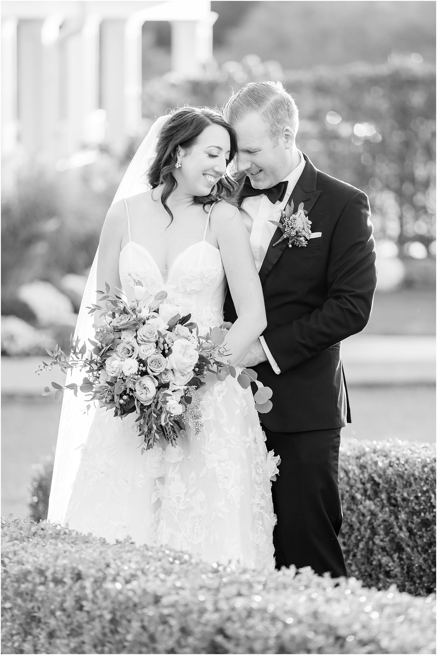 groom stands behind bride holding her hips leaning head into her 