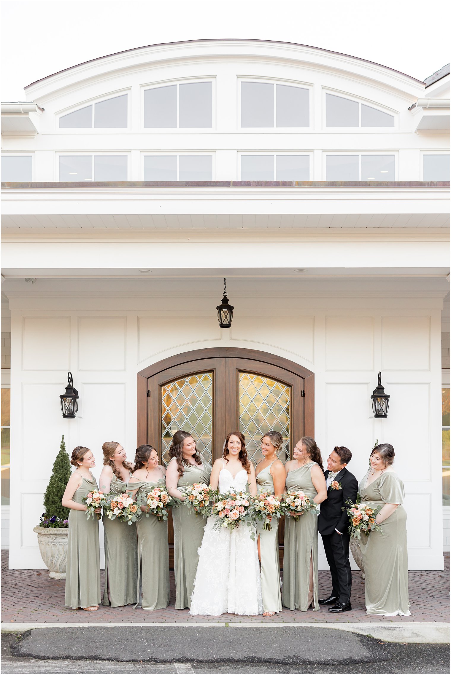 bride stands with bridesmaids and bridesman in sage green