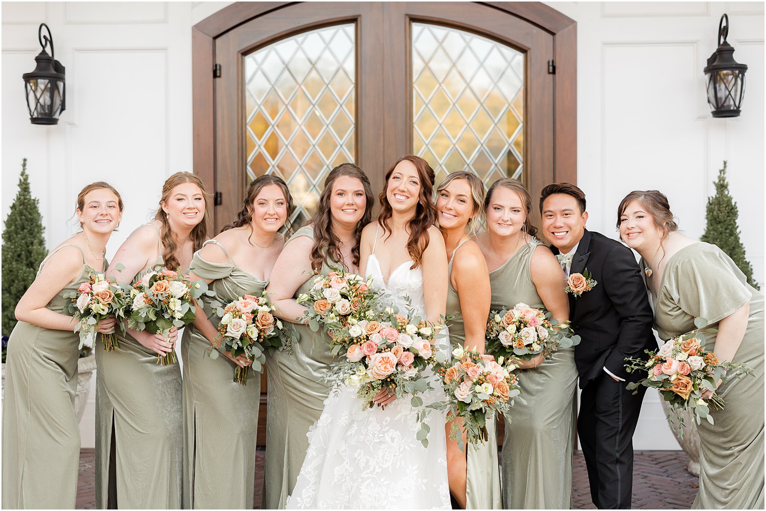 bridal party hugs bride standing outside The Mill Lakeside Manor