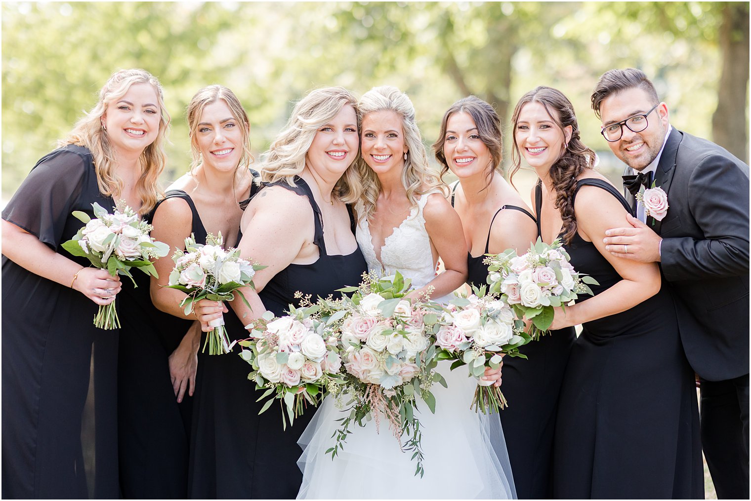 bride poses with bridesmaids in black dresses and black suits 