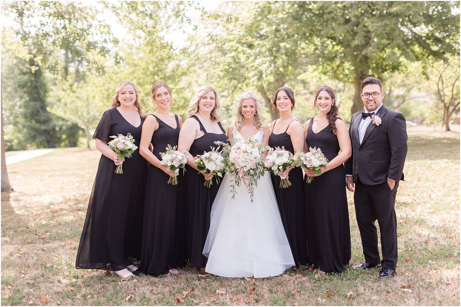 bride stands with bridesmaids in black dresses before fall wedding at the Mill Lakeside Manor