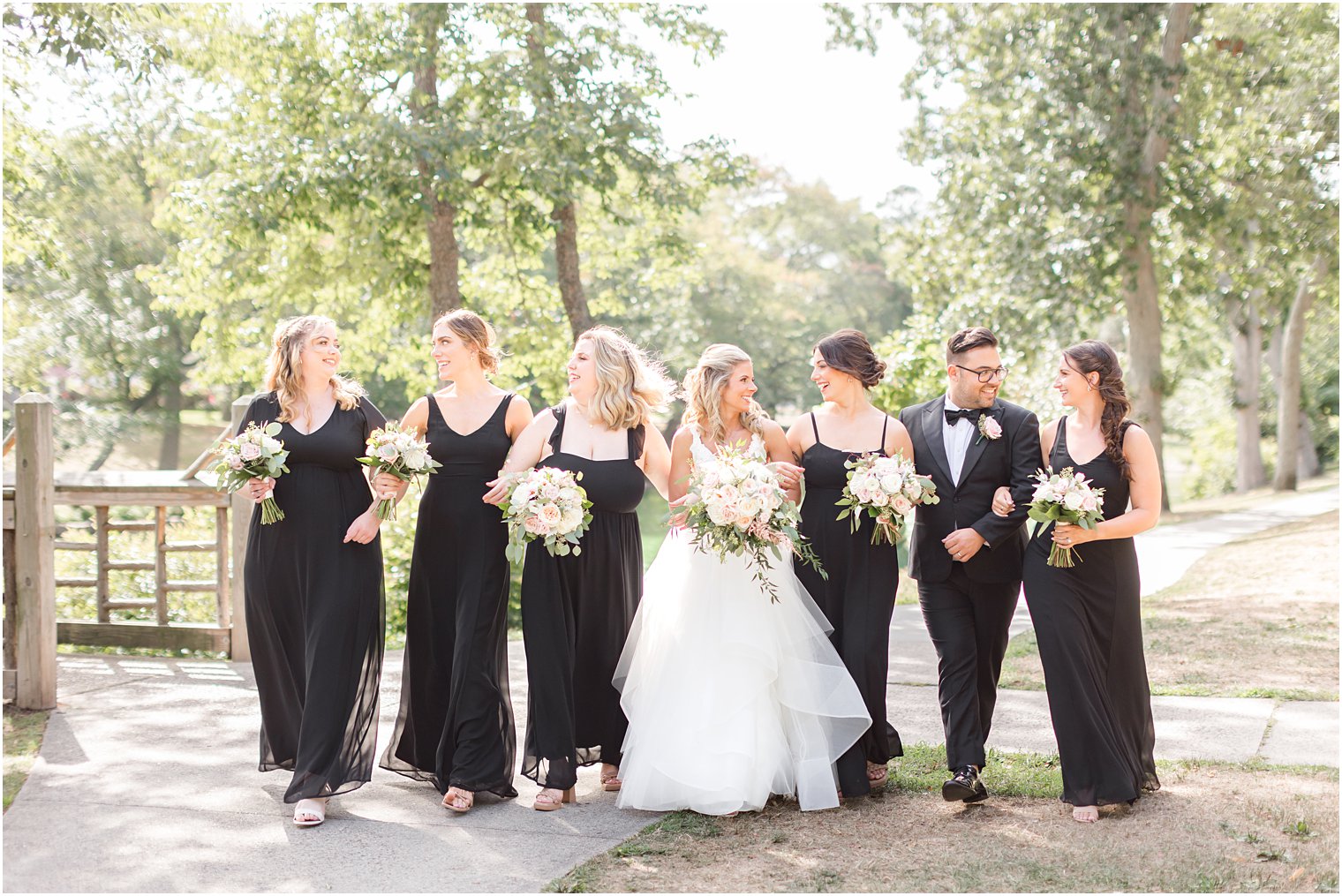 bride walks with bridesmaids in black dresses before NJ wedding 