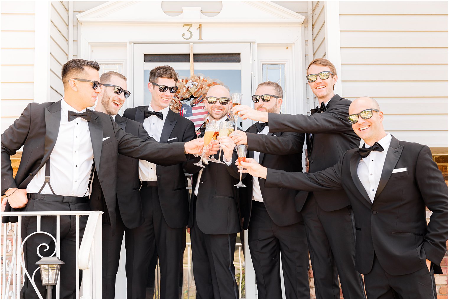 groomsmen toast with champagne outside home