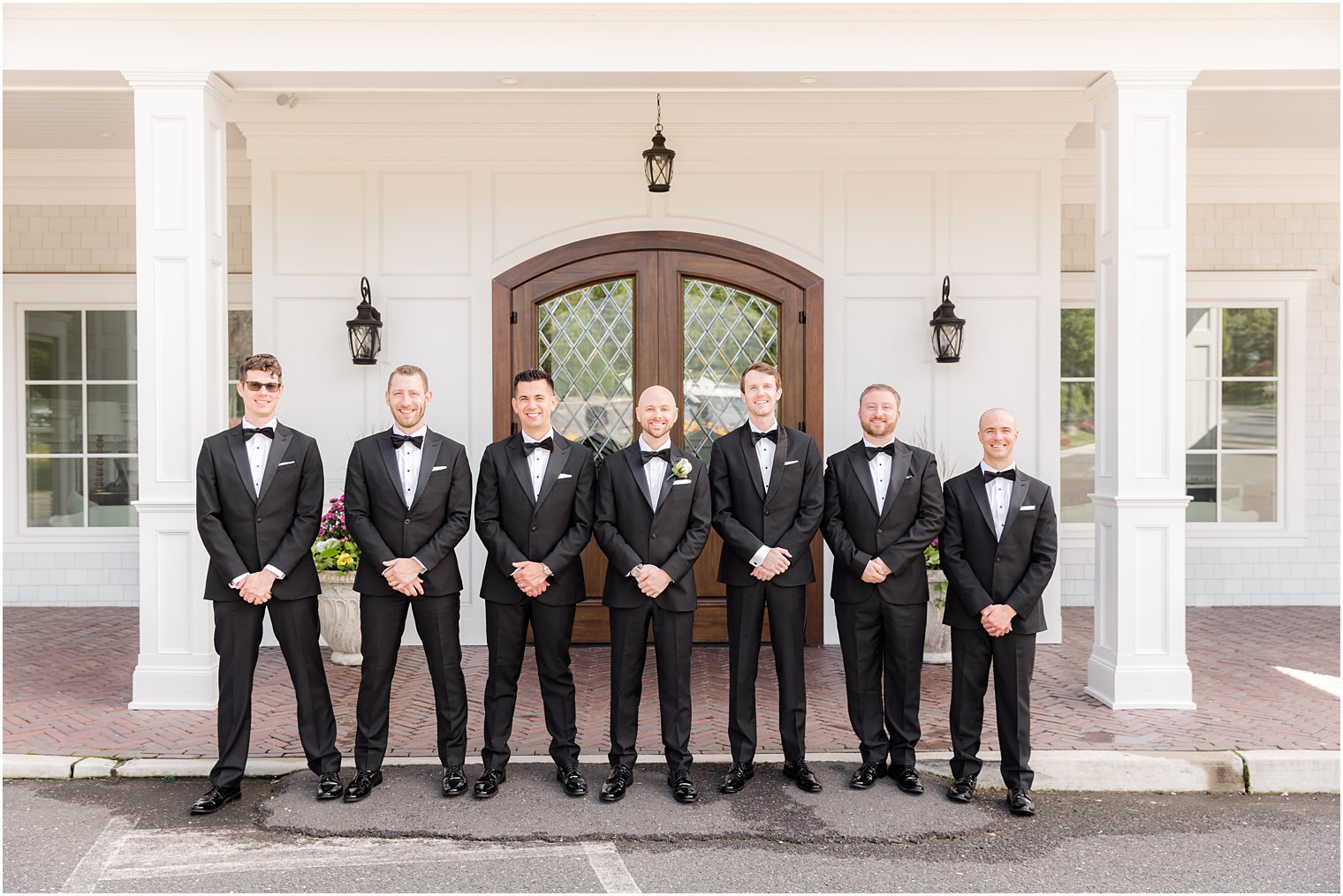 groom and groomsmen stand outside wooden door of The Mill Lakeside Manor