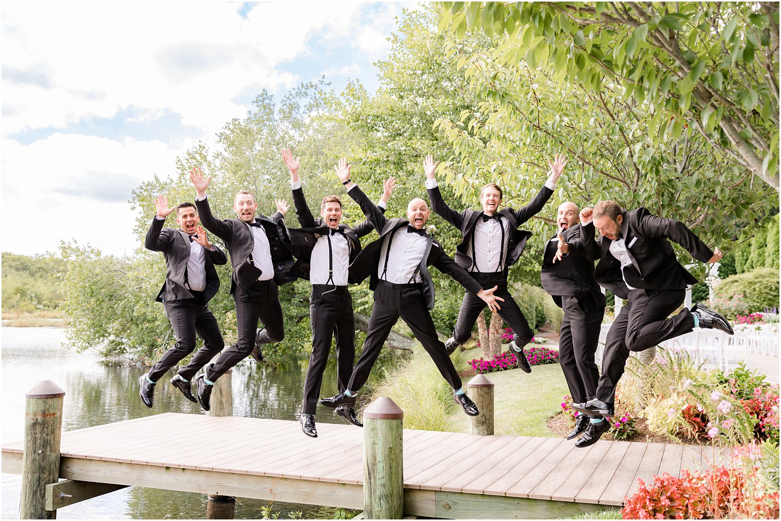 groomsmen jump on wooden dock at The Mill Lakeside Manor