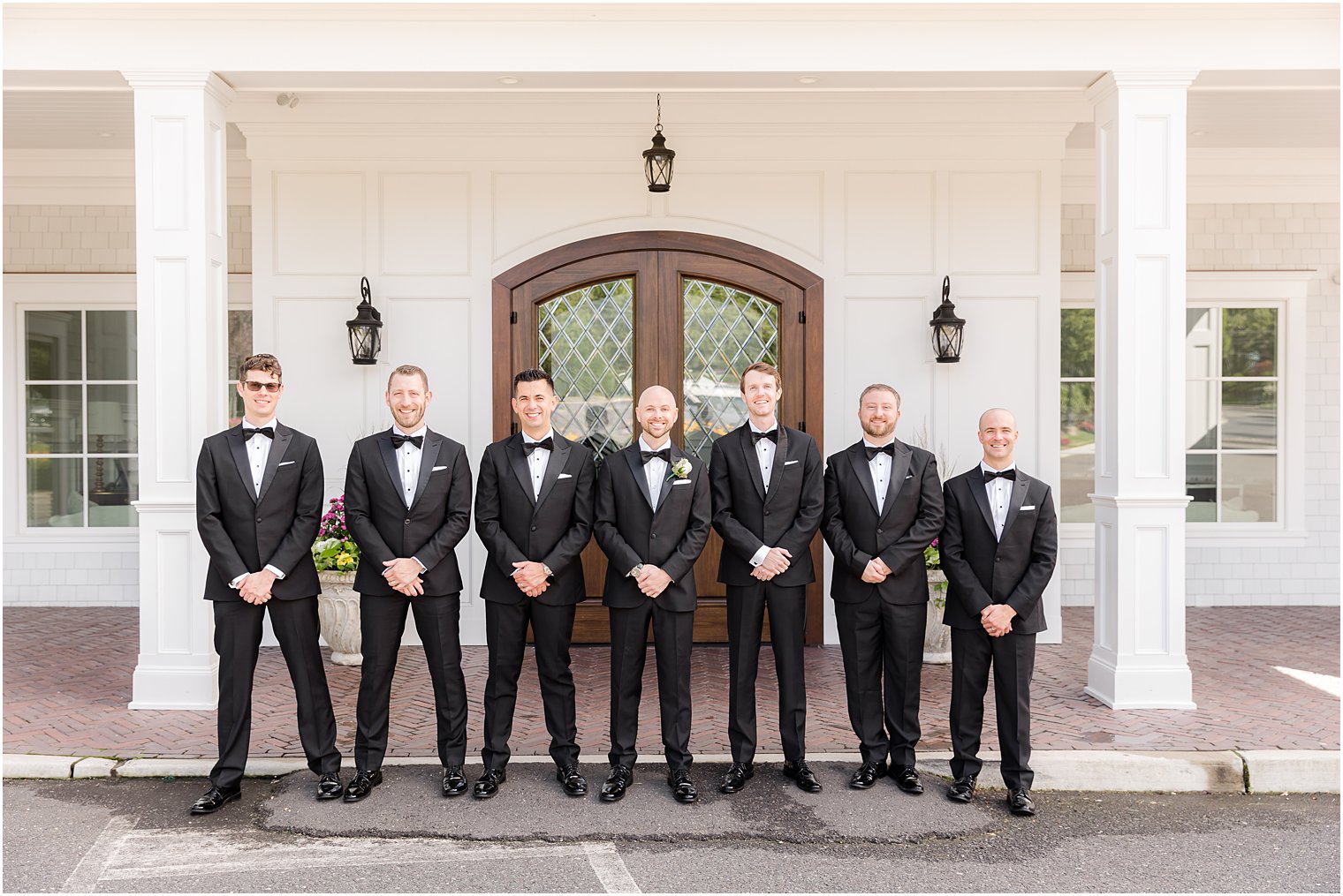 groom stands with groomsmen outside wooden door at The Mill Lakeside Manor
