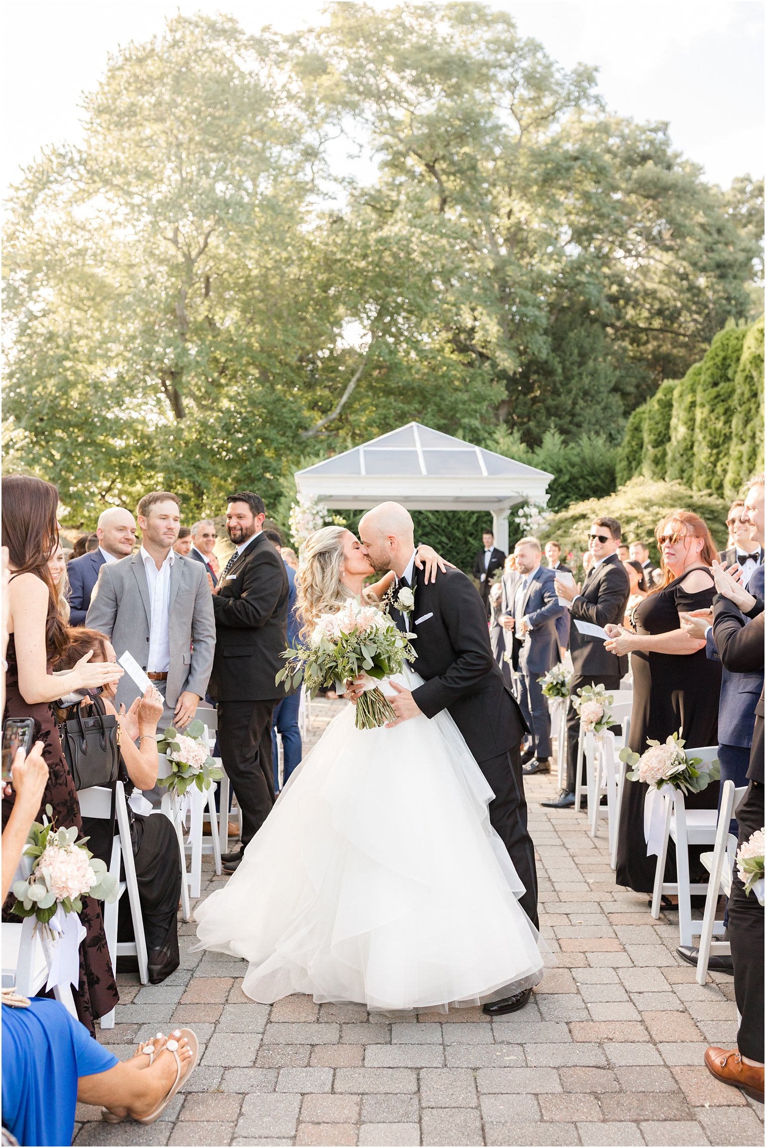 bride and groom kiss walking up aisle after ceremony