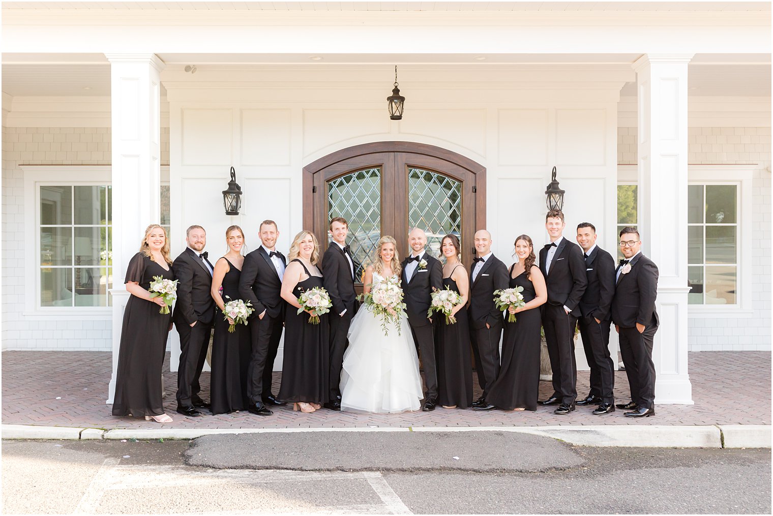 newlyweds pose with wedding party in black outfits at The Mill Lakeside Manor