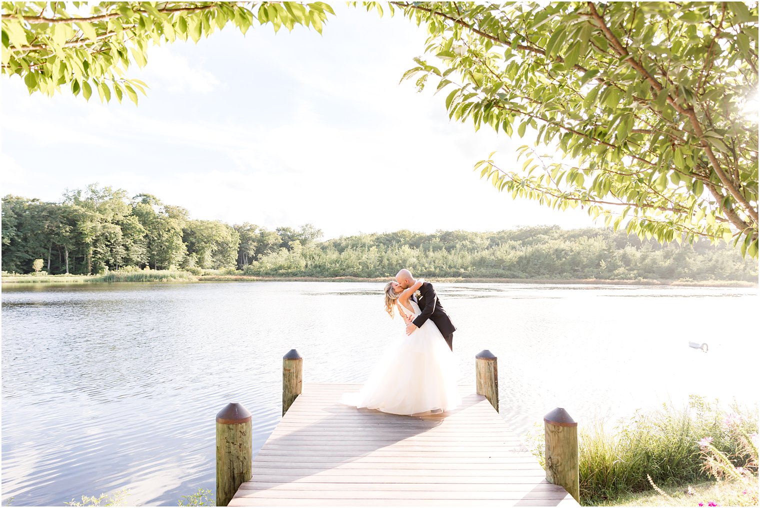 groom dips bride during kiss on wooden dock at The Mill Lakeside Manor