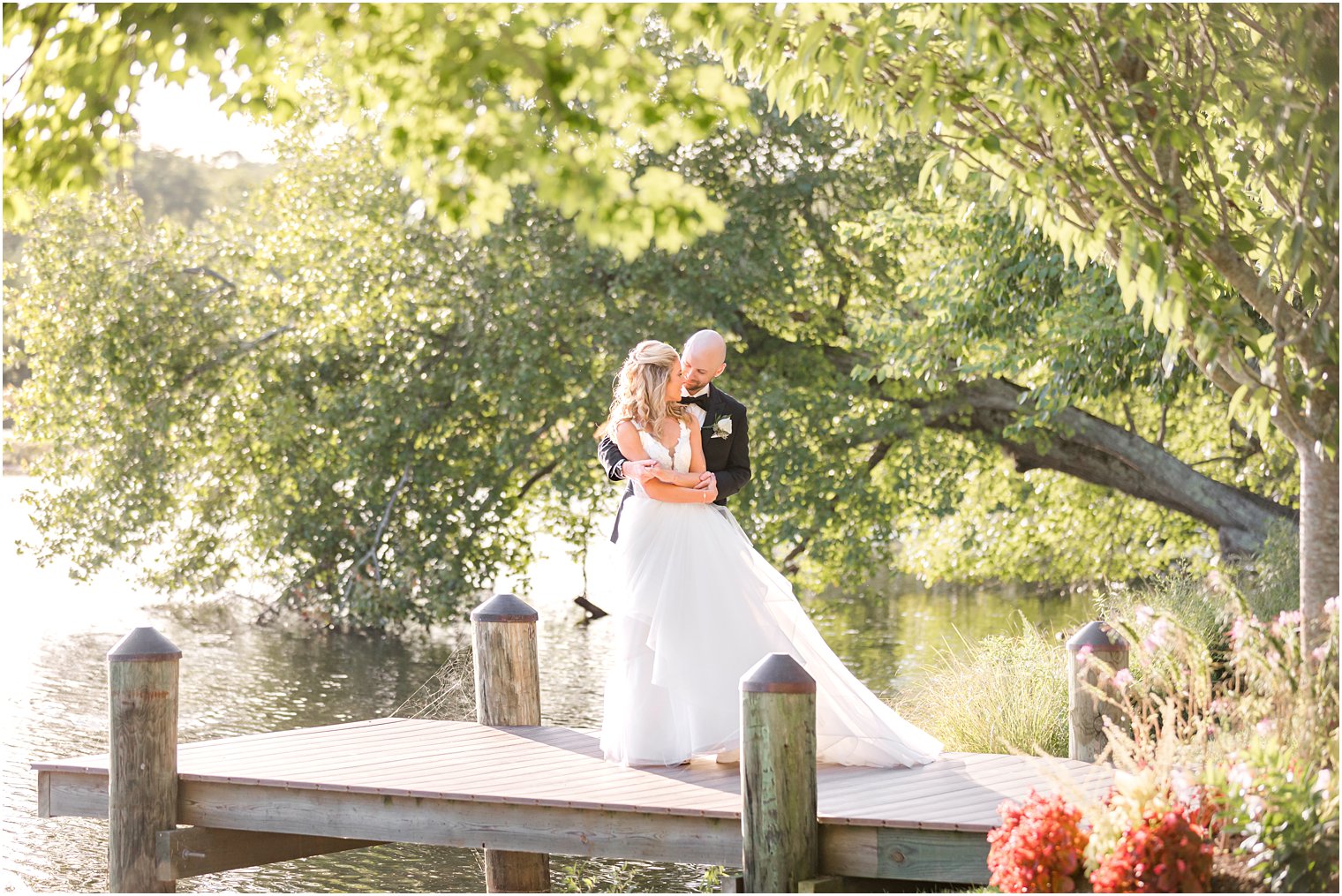 groom hugs bride from behind on dock at The Mill Lakeside Manor