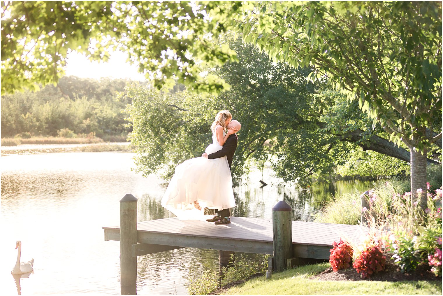 groom lifts bride up on wooden dock at The Mill Lakeside Manor