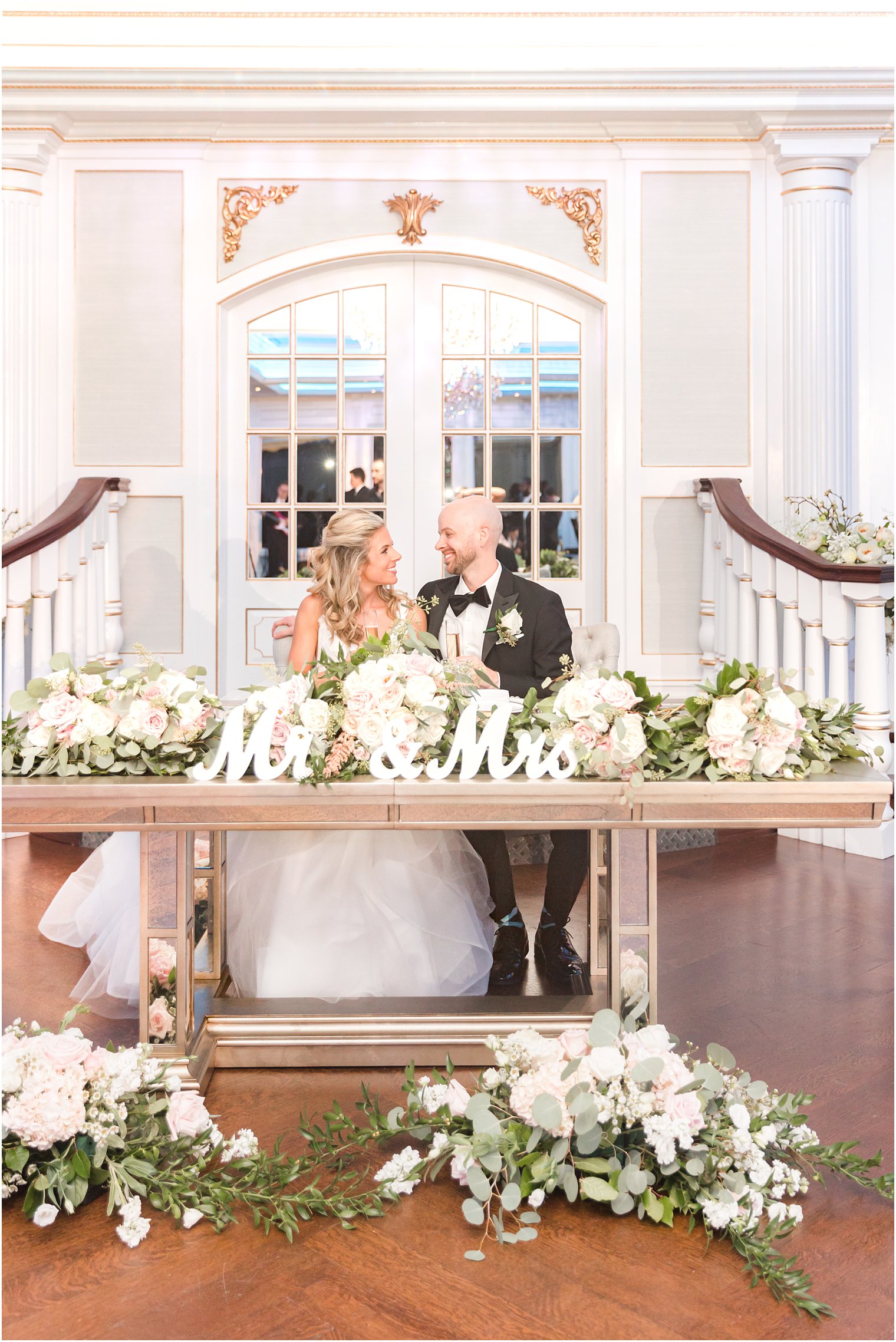 newlyweds smile together at sweetheart table